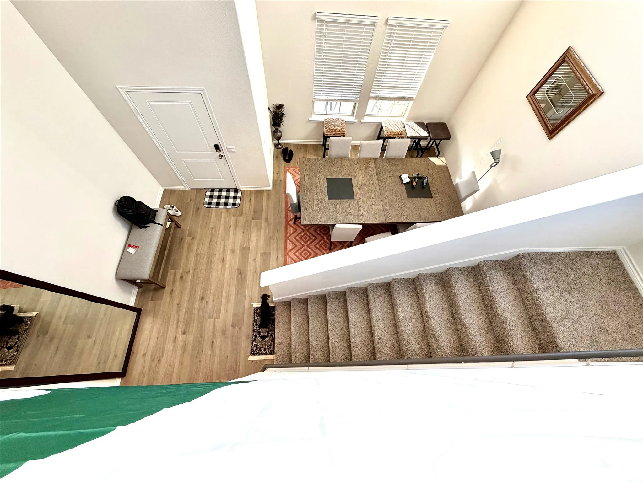 Wood-finish flooring in an open-concept living area with a dining space, featuring multiple windows and a carpeted staircase