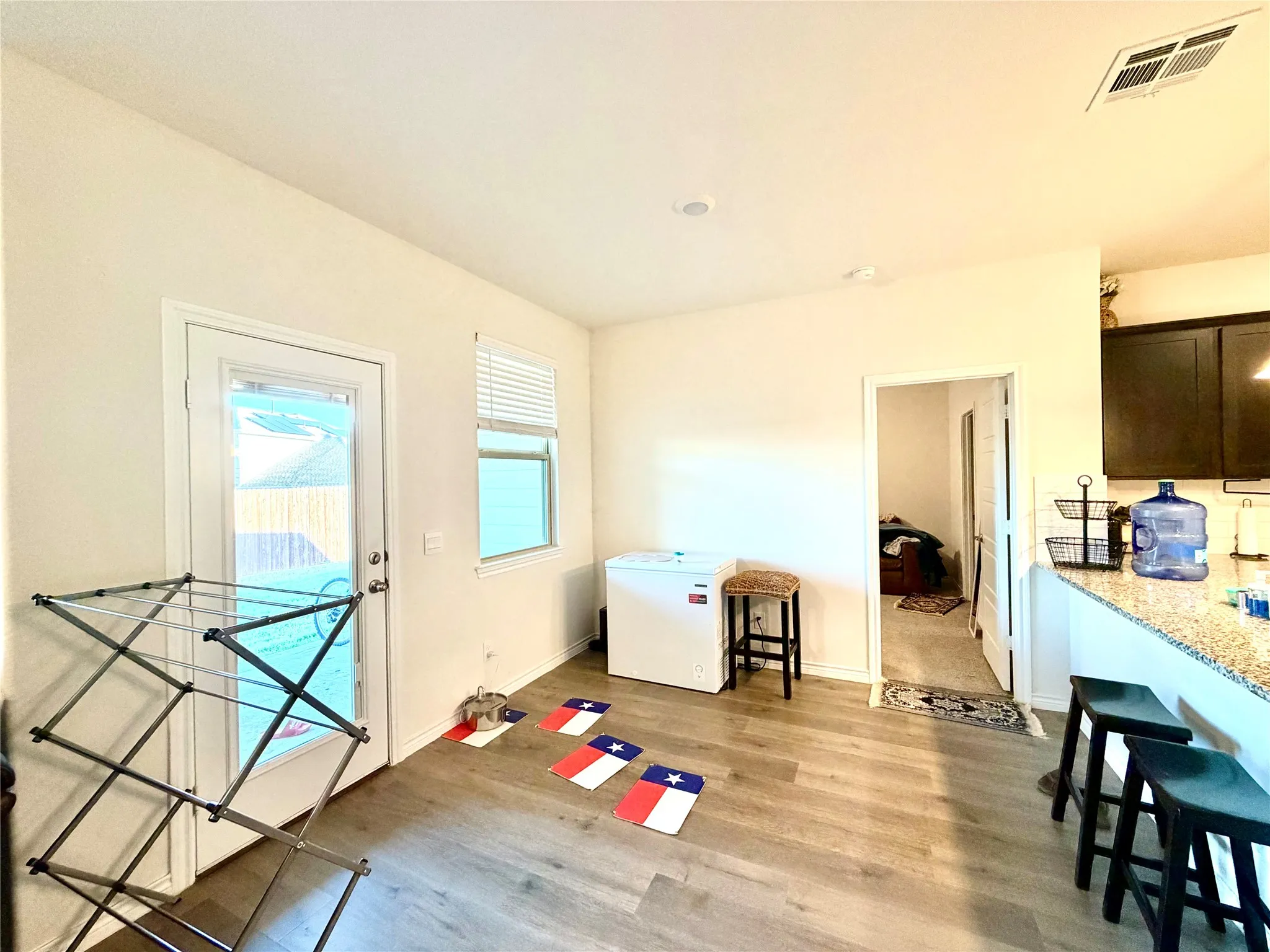 Wood-finish flooring throughout, bright recessed lighting, and a white paneled door with glass insert