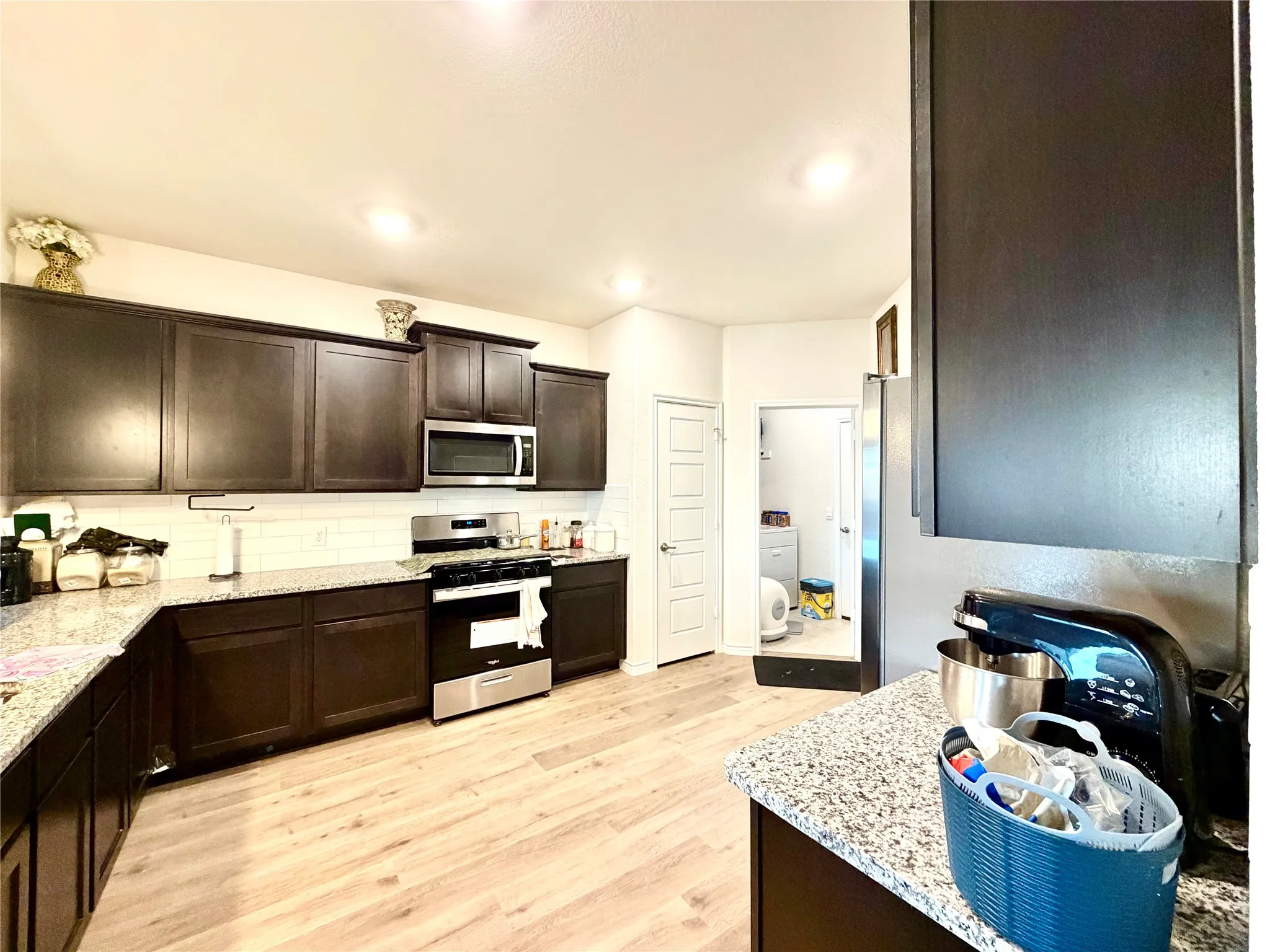 Kitchen featuring dark wood-finish cabinetry, light-toned wood-finish flooring, and white subway tile backsplash