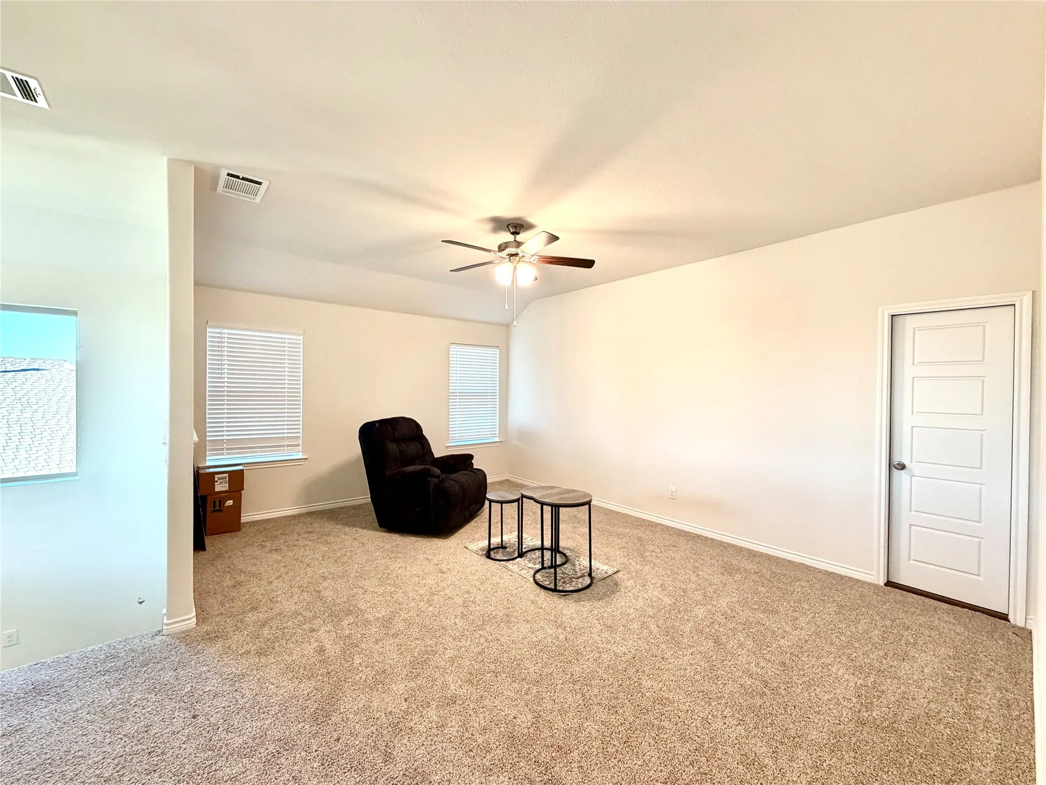 Vaulted ceiling with a ceiling fan, carpeted flooring, multiple windows with blinds, and paneled interior doors