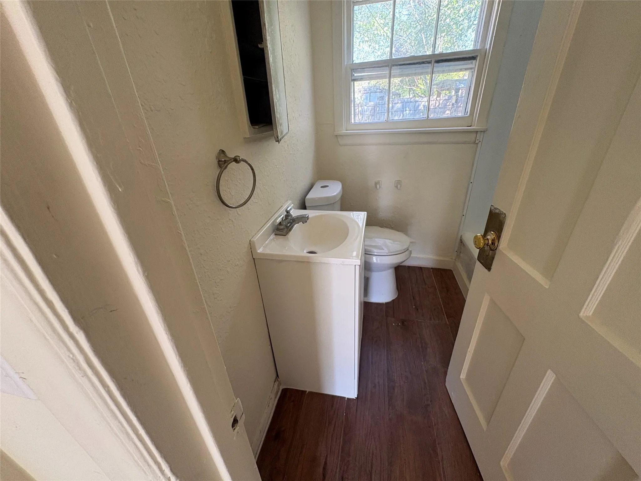 White vanity with integrated sink, wood-finish flooring, and a single window