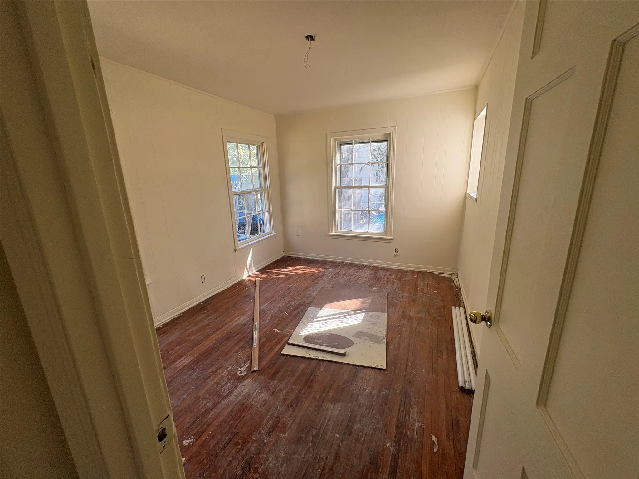 Hardwood flooring, painted walls, two double-hung windows, and a panel door
