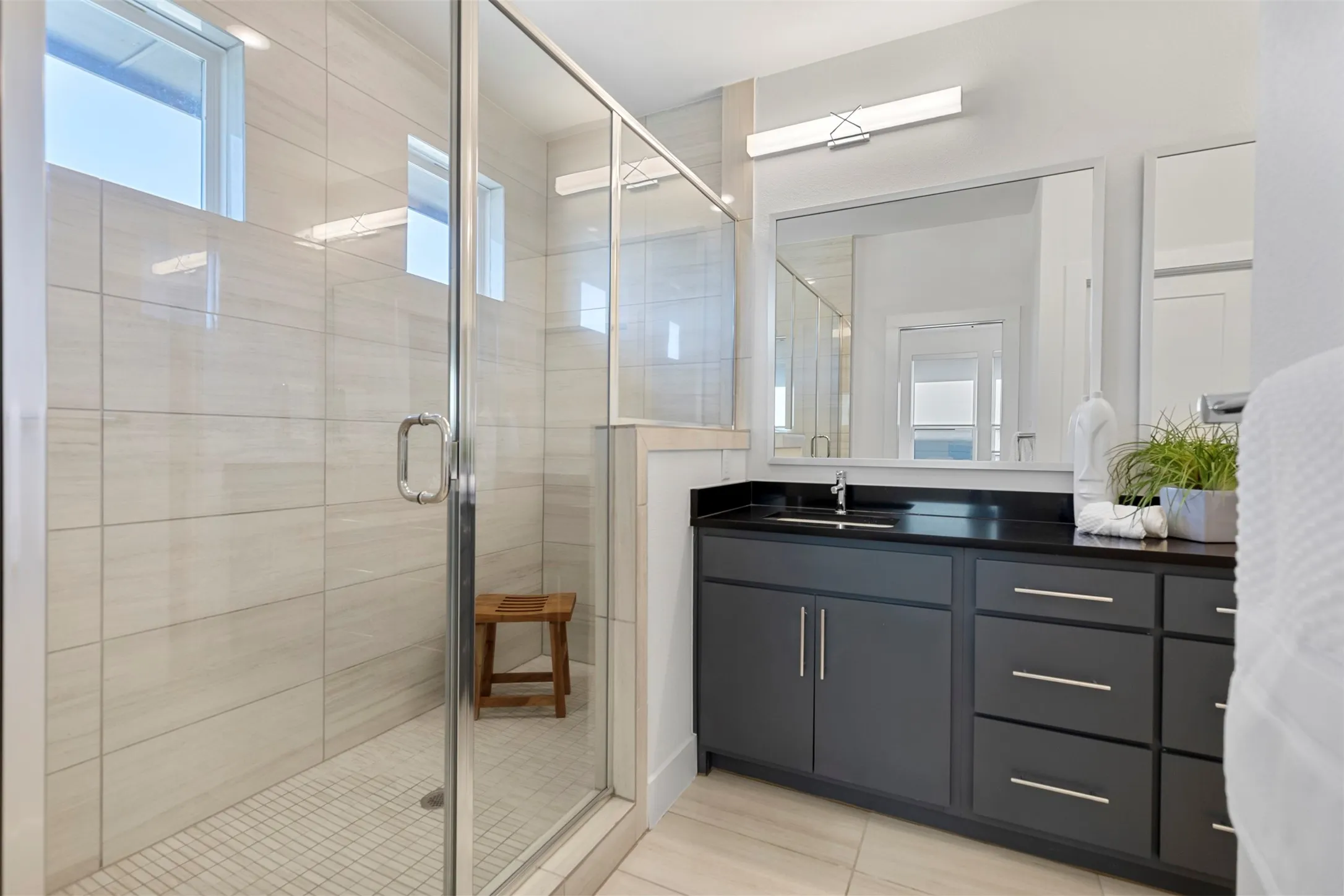 This stunning, expansive walk-in shower features high-end designer tiling throughout and is equipped with a luxurious rainfall showerhead, creating a spa-like retreat within the home.