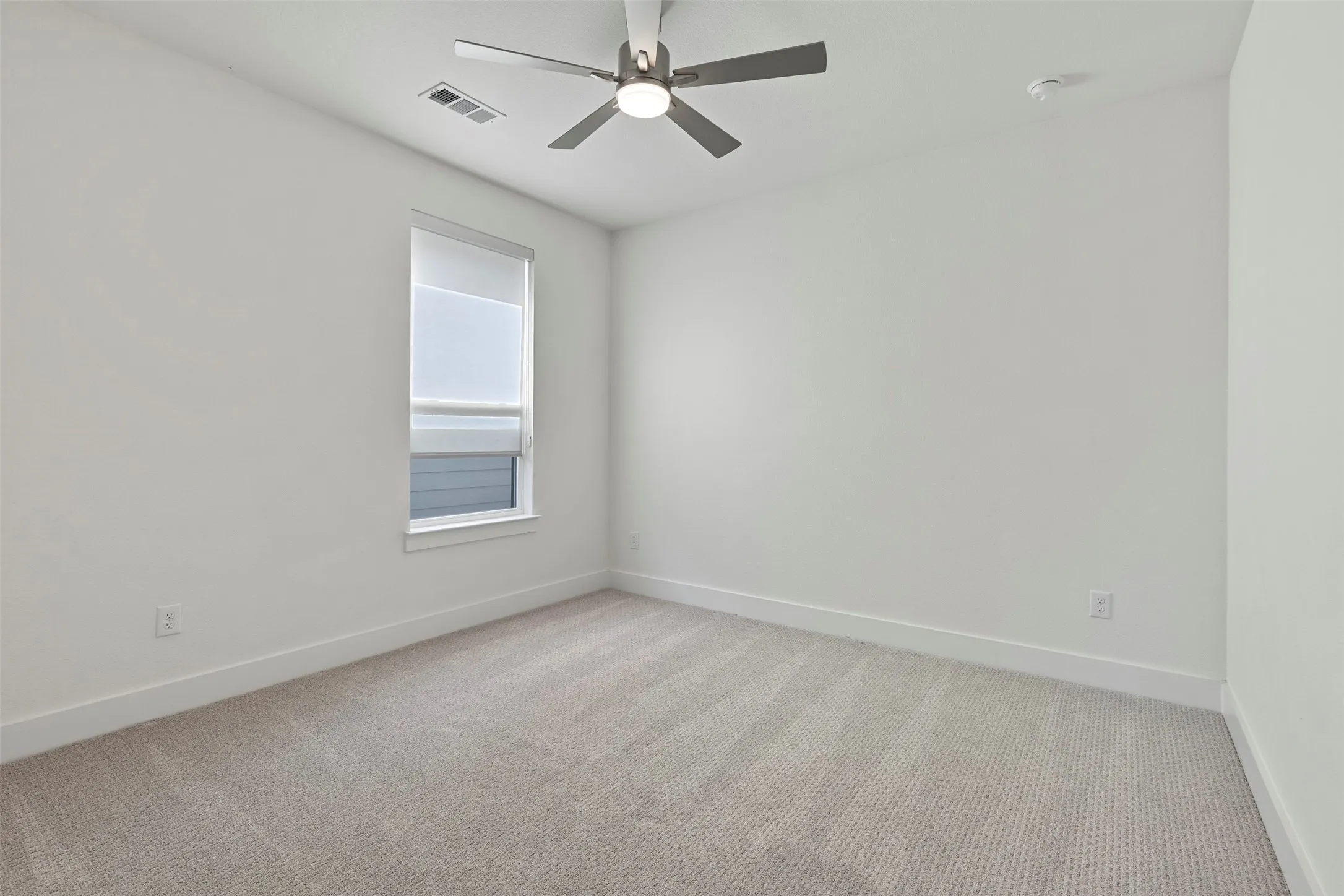 This room serves as a bright and spacious secondary bedroom, featuring ample natural light and neutral finishes that make it a versatile space for guests or family members.