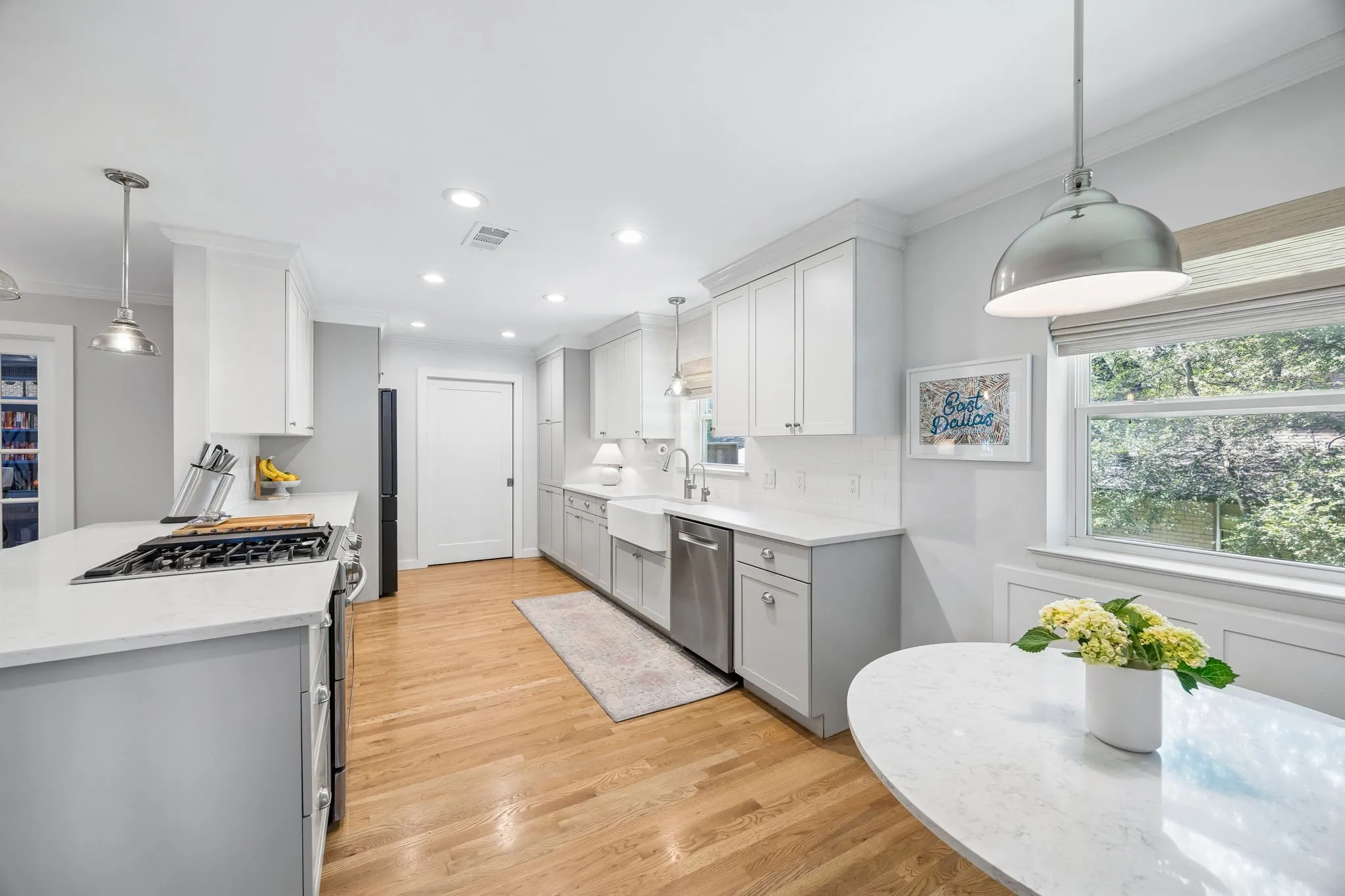 Light wood-finish flooring, white shaker cabinetry, white countertops, stainless steel appliances, and recessed lighting