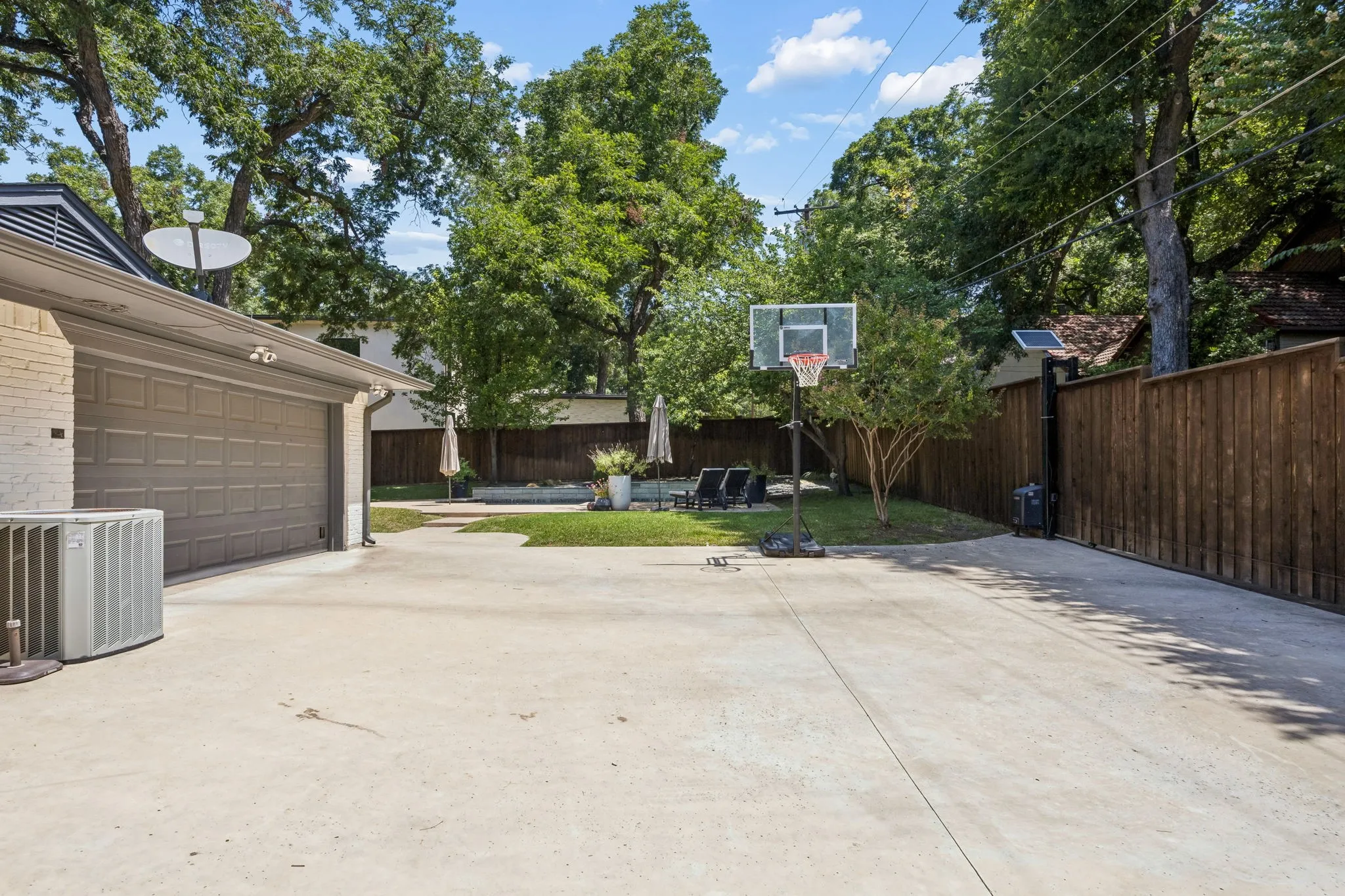Spacious concrete driveway, attached two-car garage with a paneled door, privacy fence, and manicured lawn