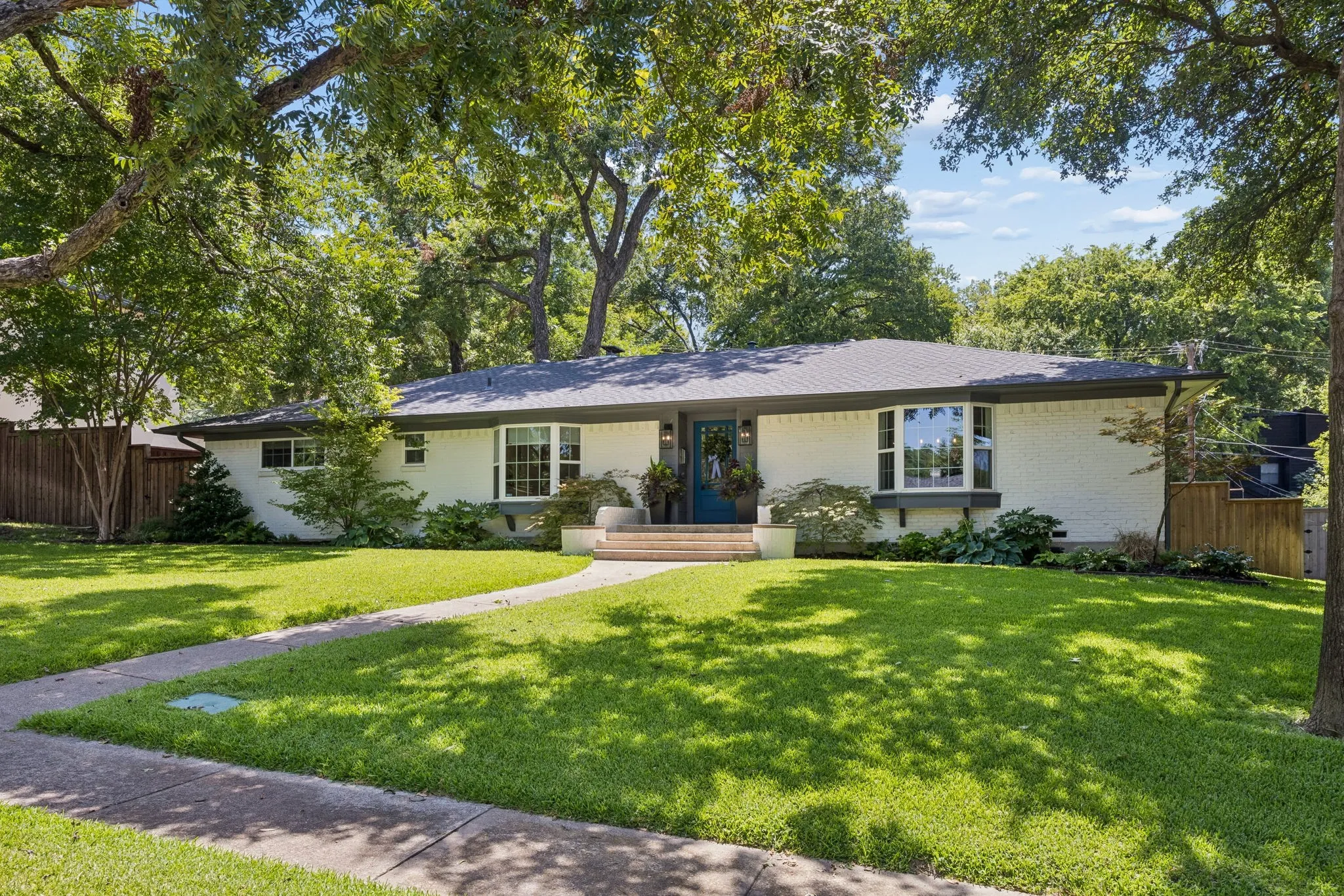 Ranch-style exterior with a dark shingle roof and white brick façade