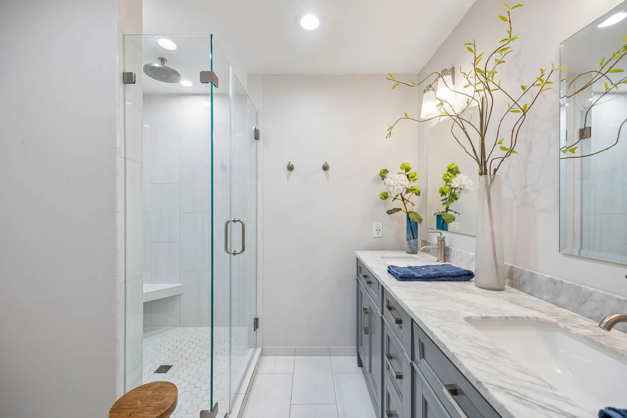 Glass-enclosed shower with a built-in bench, hexagon tile floor, and ceiling-mounted rain shower head