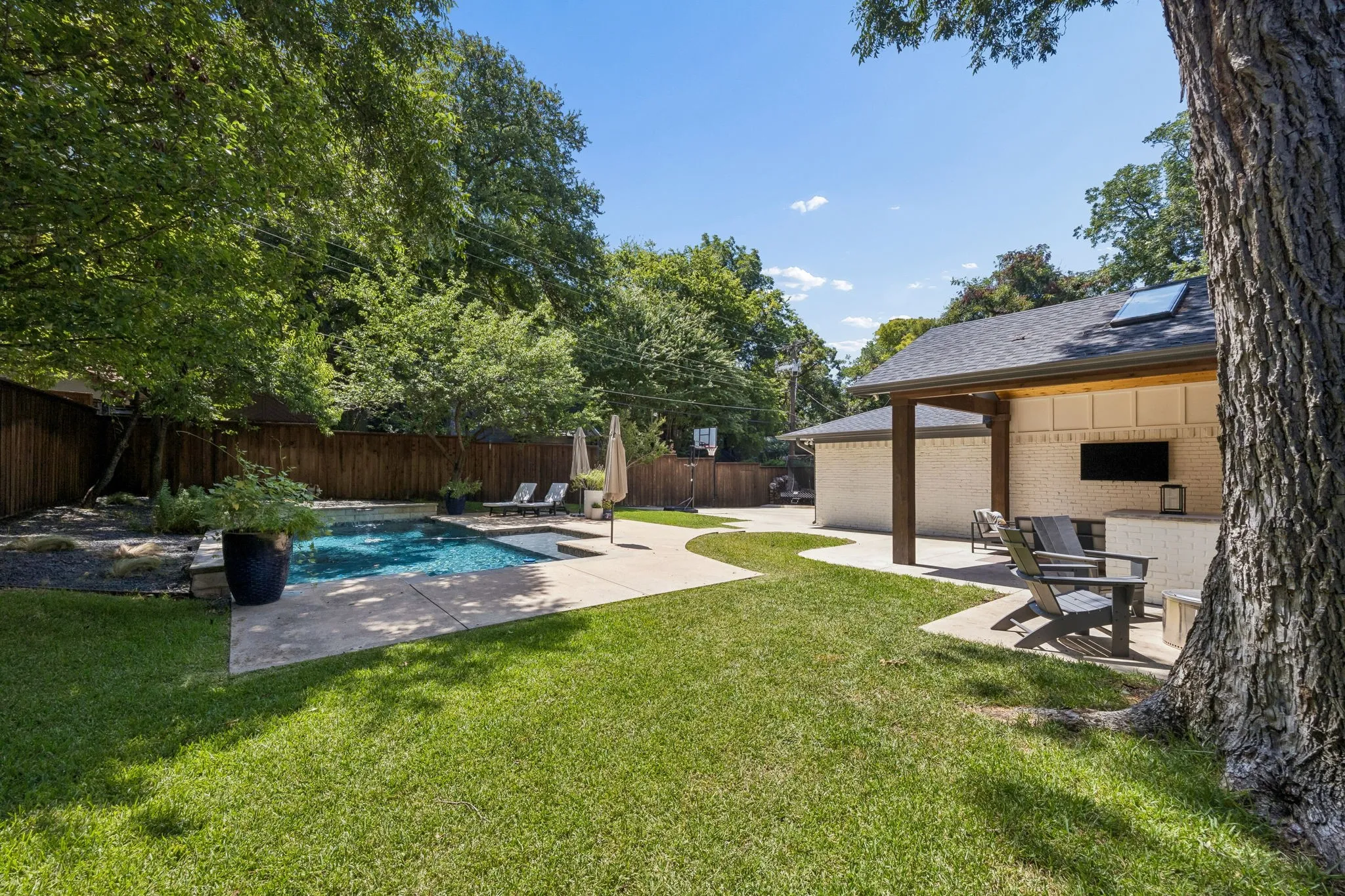 Outdoor living area featuring a swimming pool, covered patio, outdoor kitchen, and manicured lawn