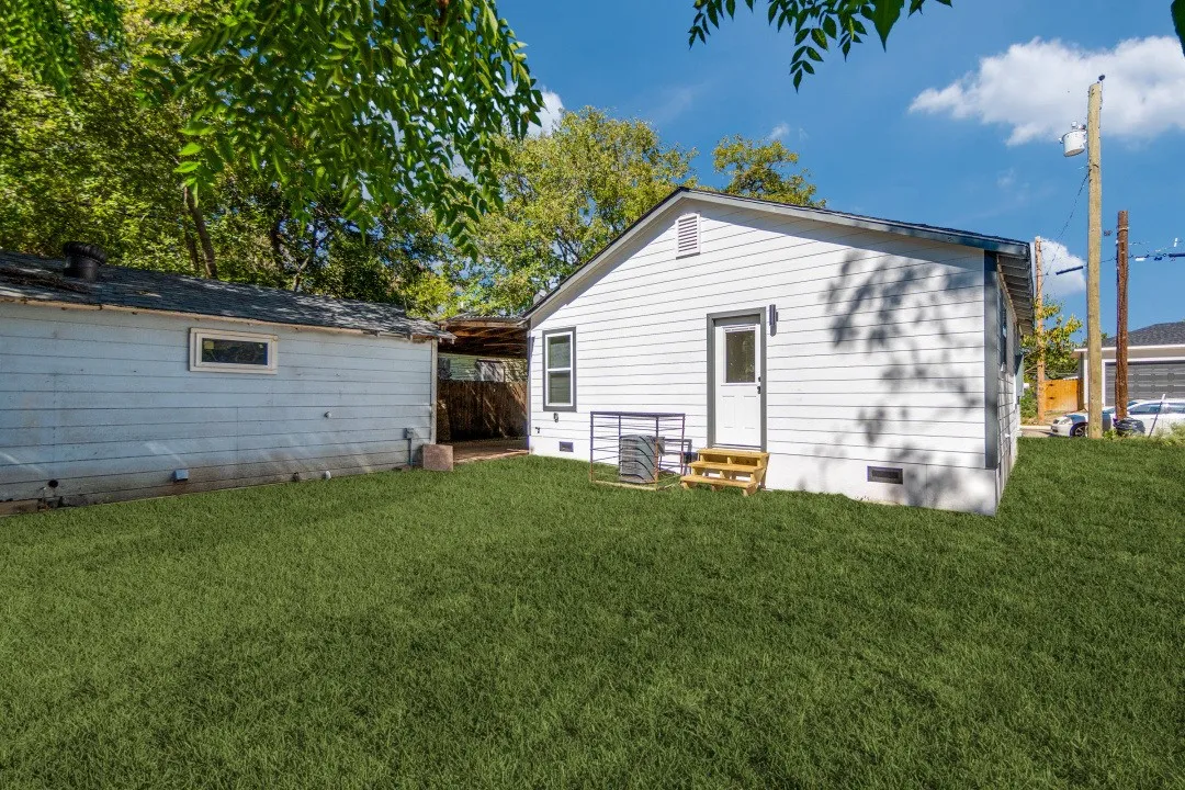 Expansive grassy yard with a white siding exterior and a separate utility building