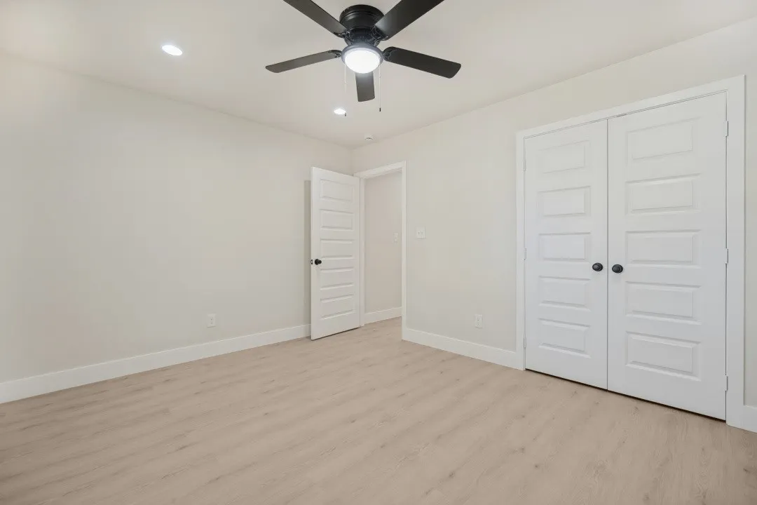 Recessed ceiling lighting with a ceiling fan, light wood-finish flooring, and white paneled doors