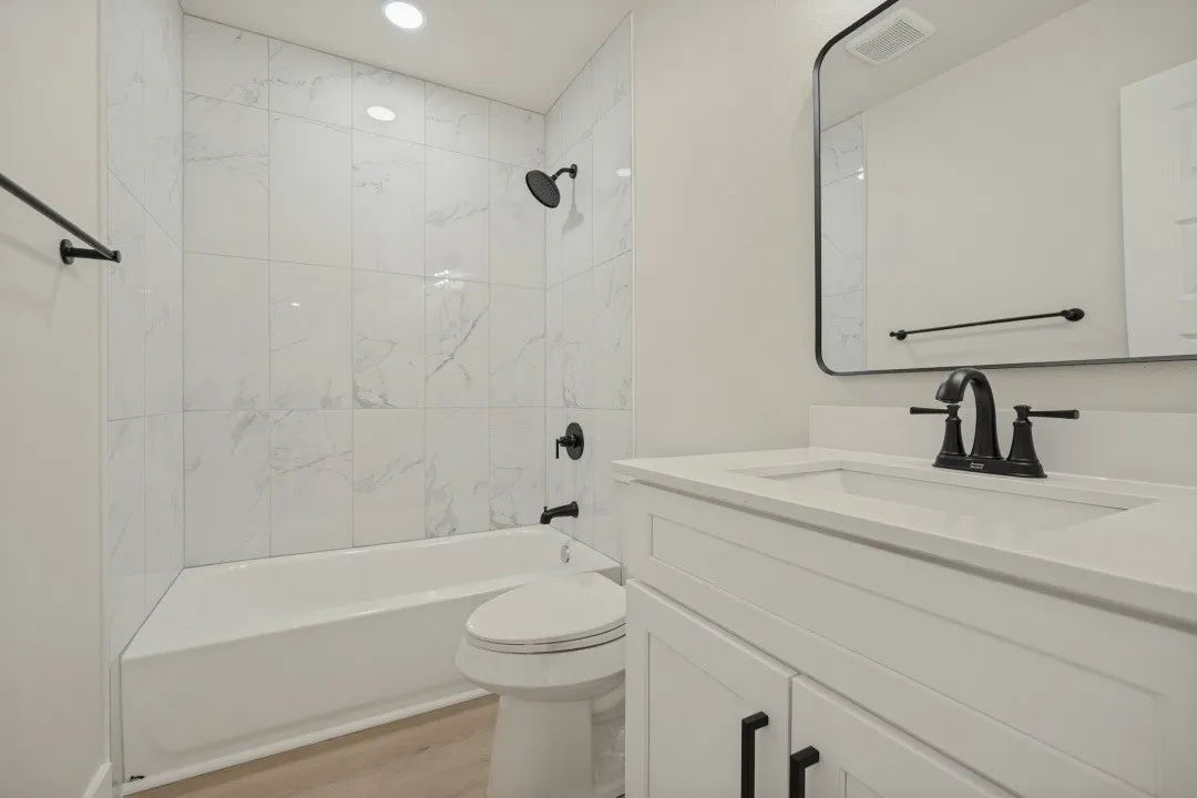 White vanity with an integrated sink, matte black faucet, and a rectangular framed mirror