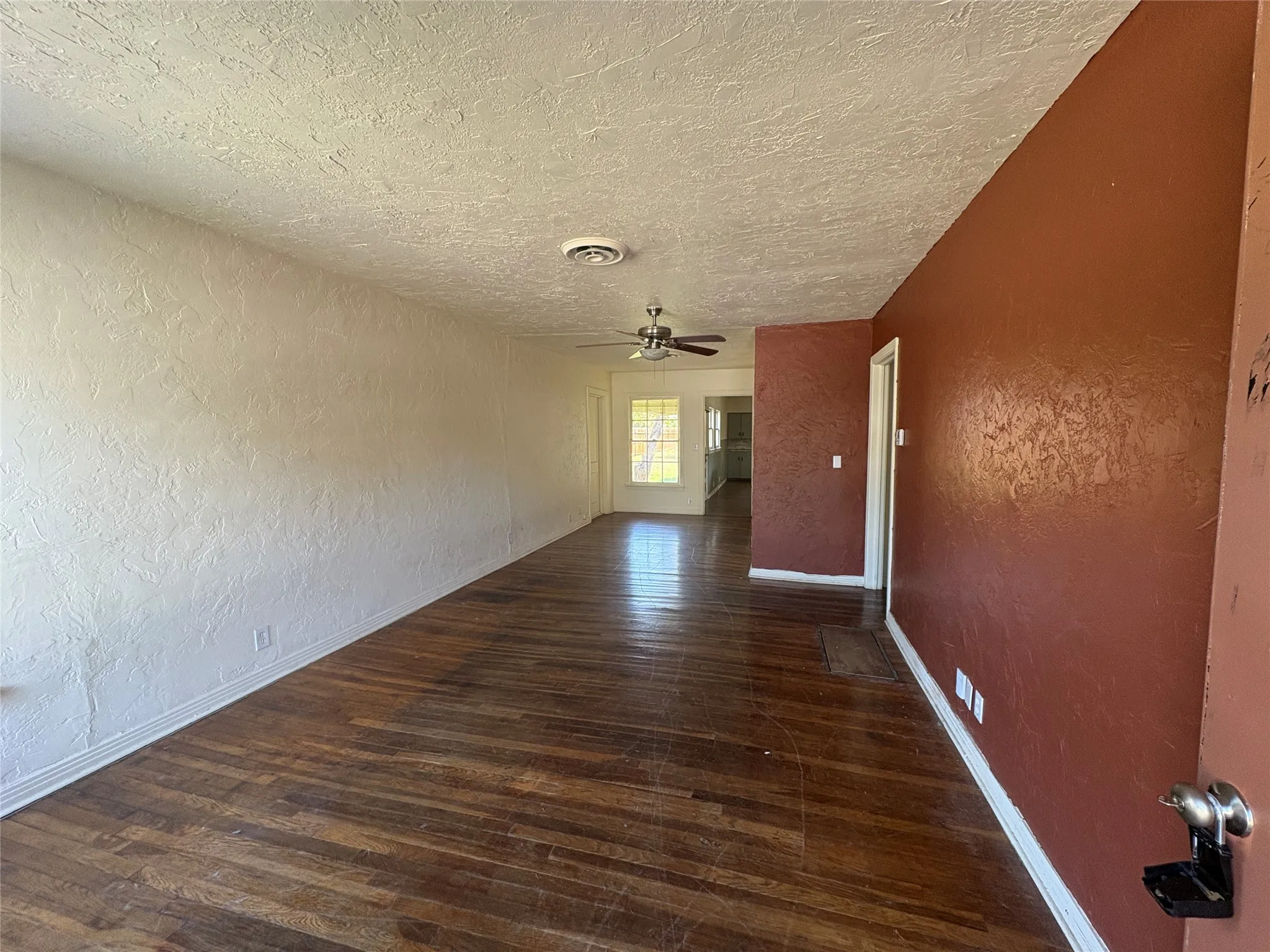 Wood-finish flooring throughout, light-toned textured walls, ceiling fan with integrated lighting, and white trim
