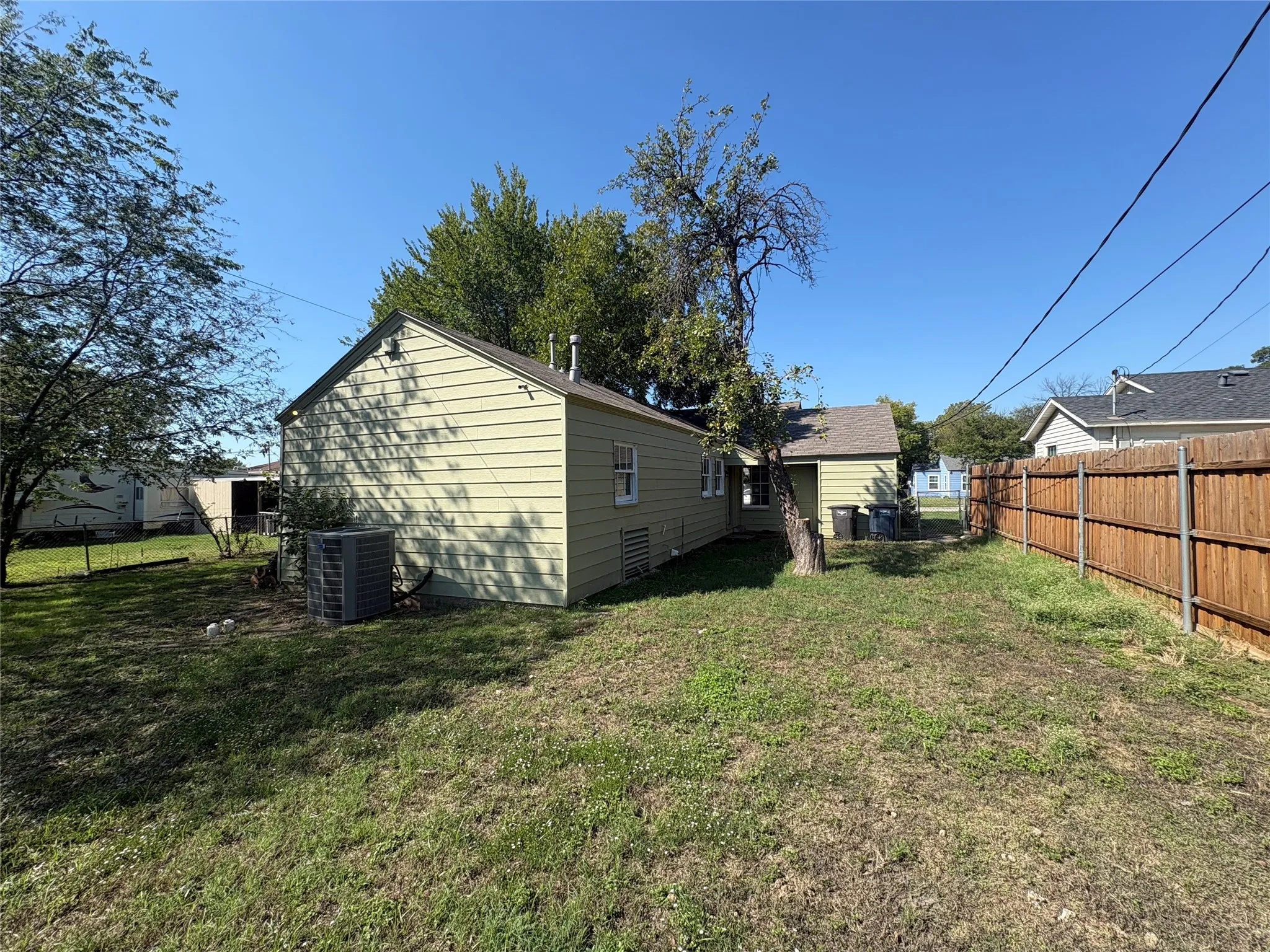 Fenced backyard with mature tree and a gabled roofline