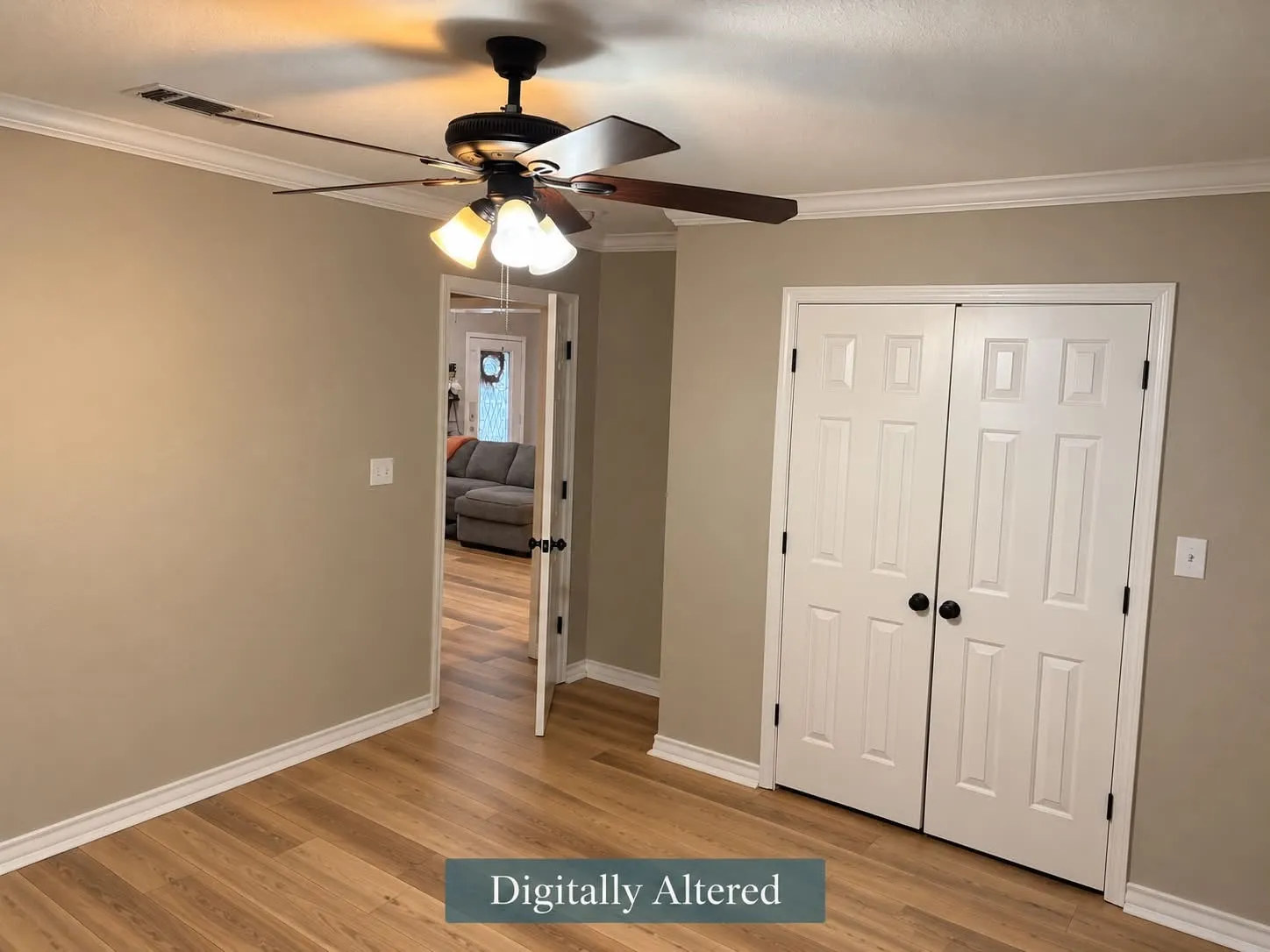 Wood-finish flooring, crown molding, ceiling fan with integrated lighting, and white bi-fold closet doors with black hardware-digitally altered to remove furniture