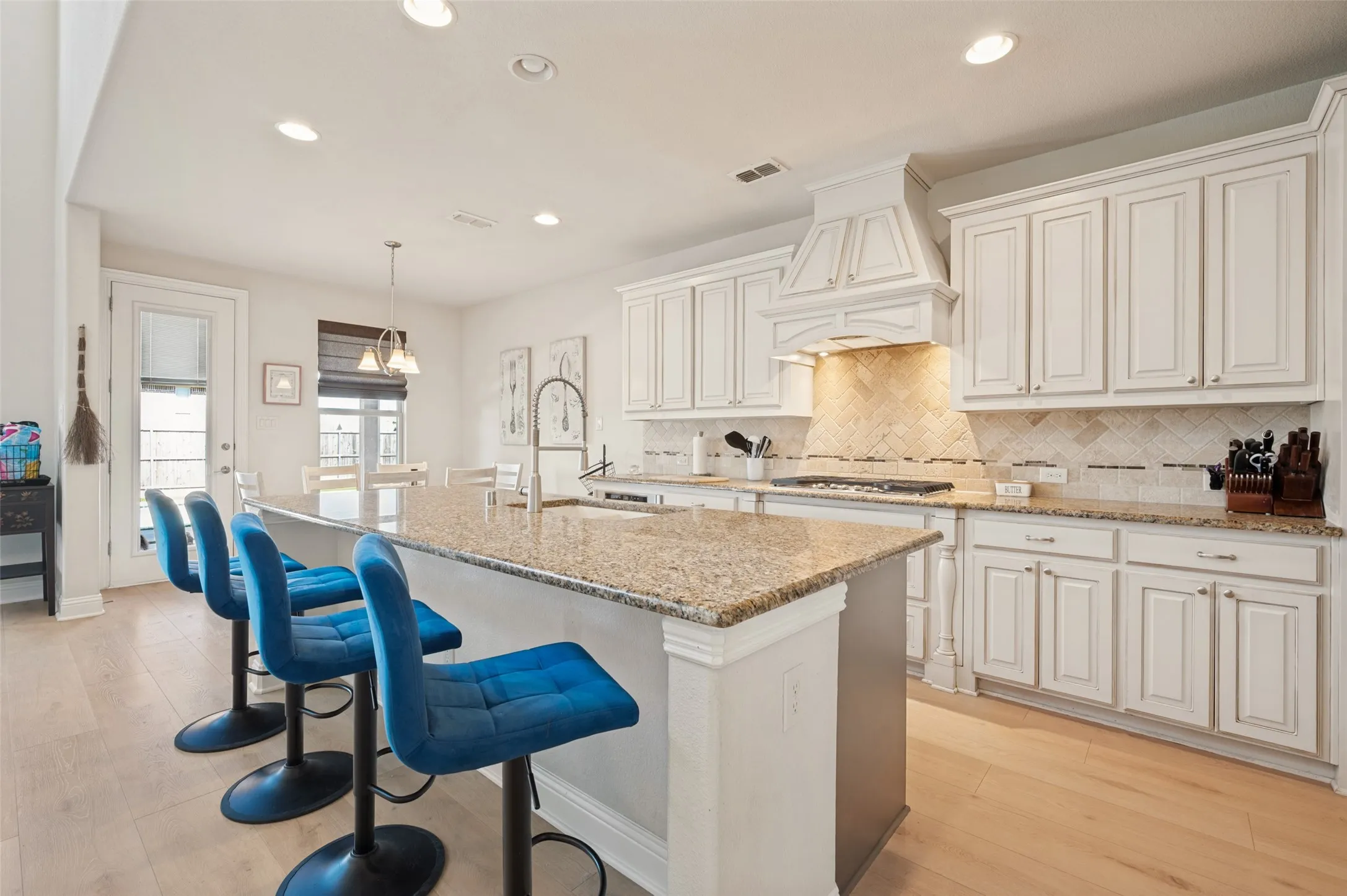 Kitchen featuring a center island with a stone countertop, white cabinetry, tile backsplash, and wood-finish flooring