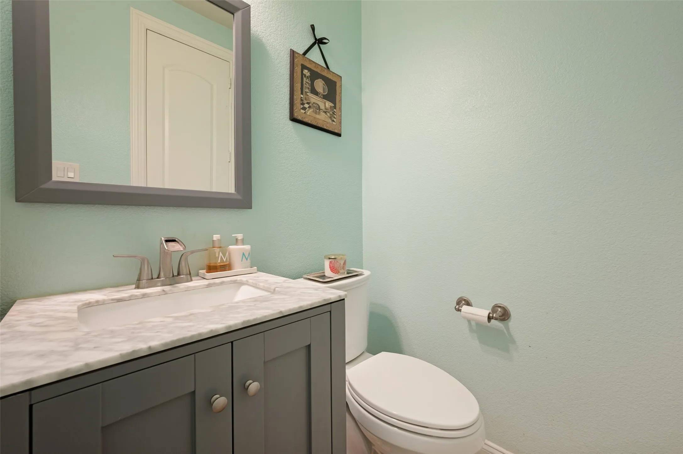 Vanity with panel-front cabinetry, integrated rectangular sink, and stone-finish countertop