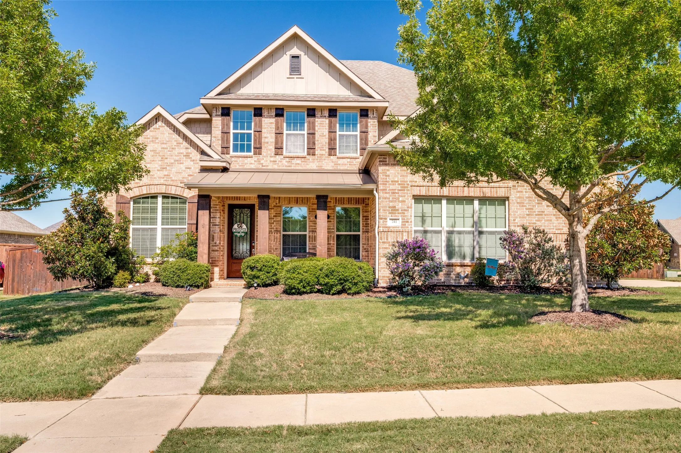 Brick exterior with contrasting wood-finish shutters, covered front porch, and a dormer window