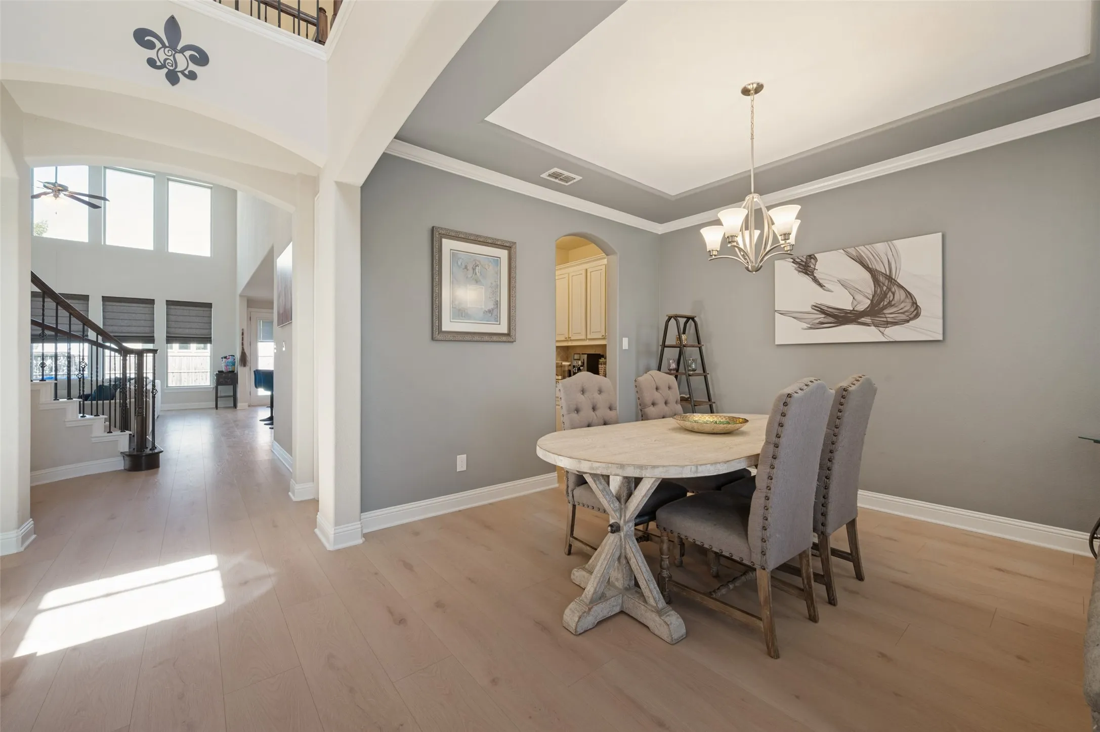 Formal dining area featuring a tray ceiling with crown molding, chandelier, and wood-finish flooring