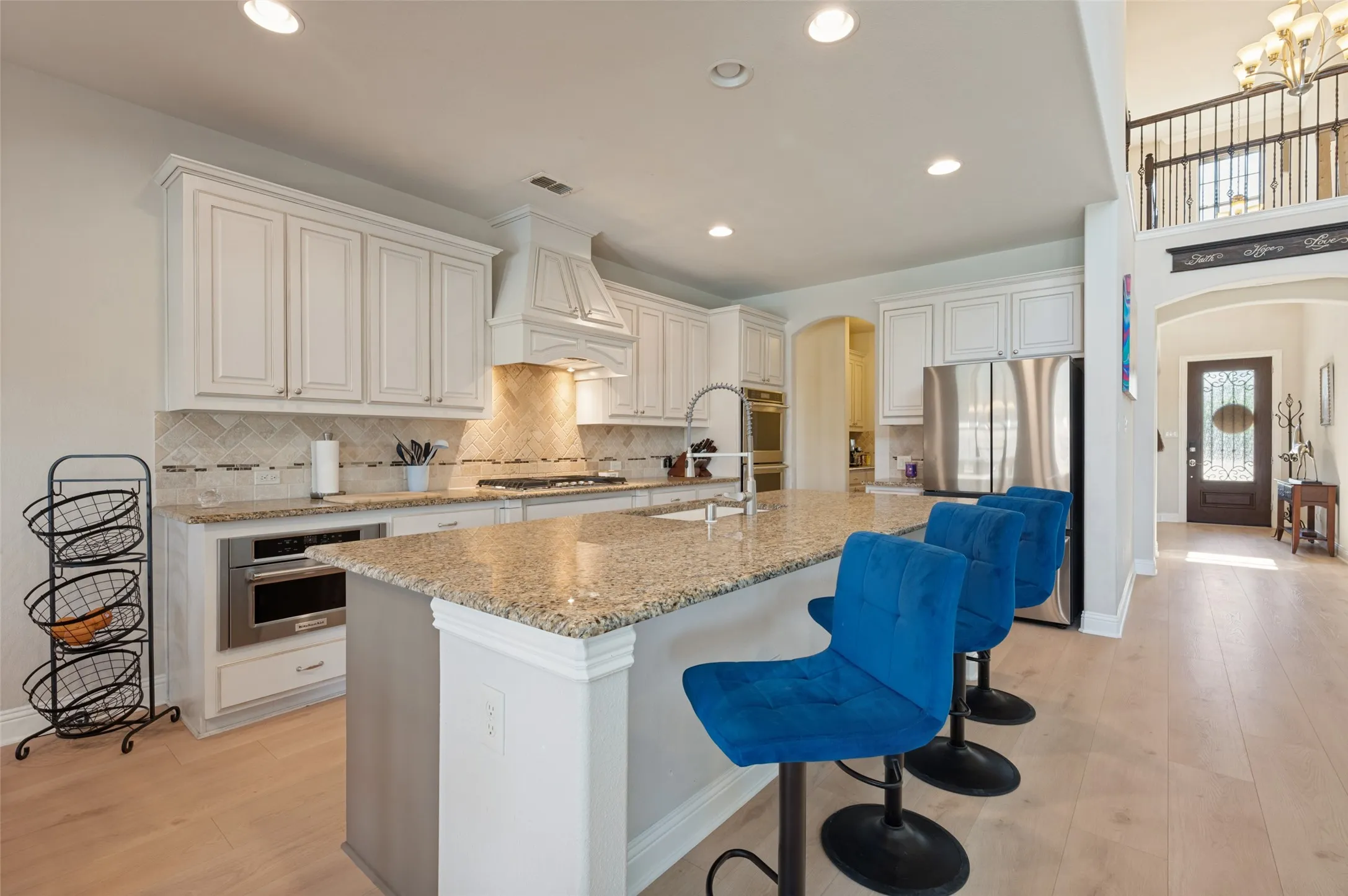Kitchen featuring white cabinetry, granite countertops, stainless steel appliances, a tile backsplash, and wood-finish flooring