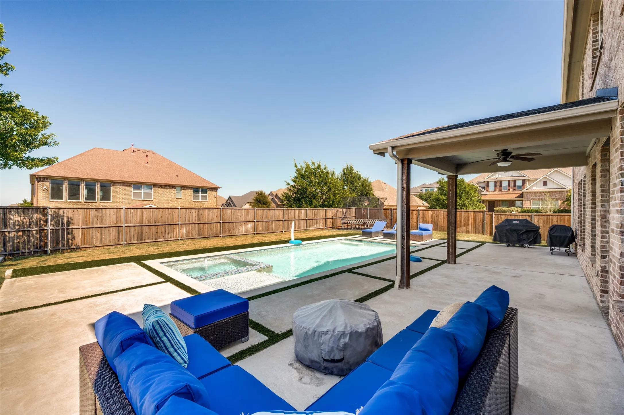Backyard featuring a rectangular pool with an integrated spa, expansive concrete patio, and covered patio with a ceiling fan