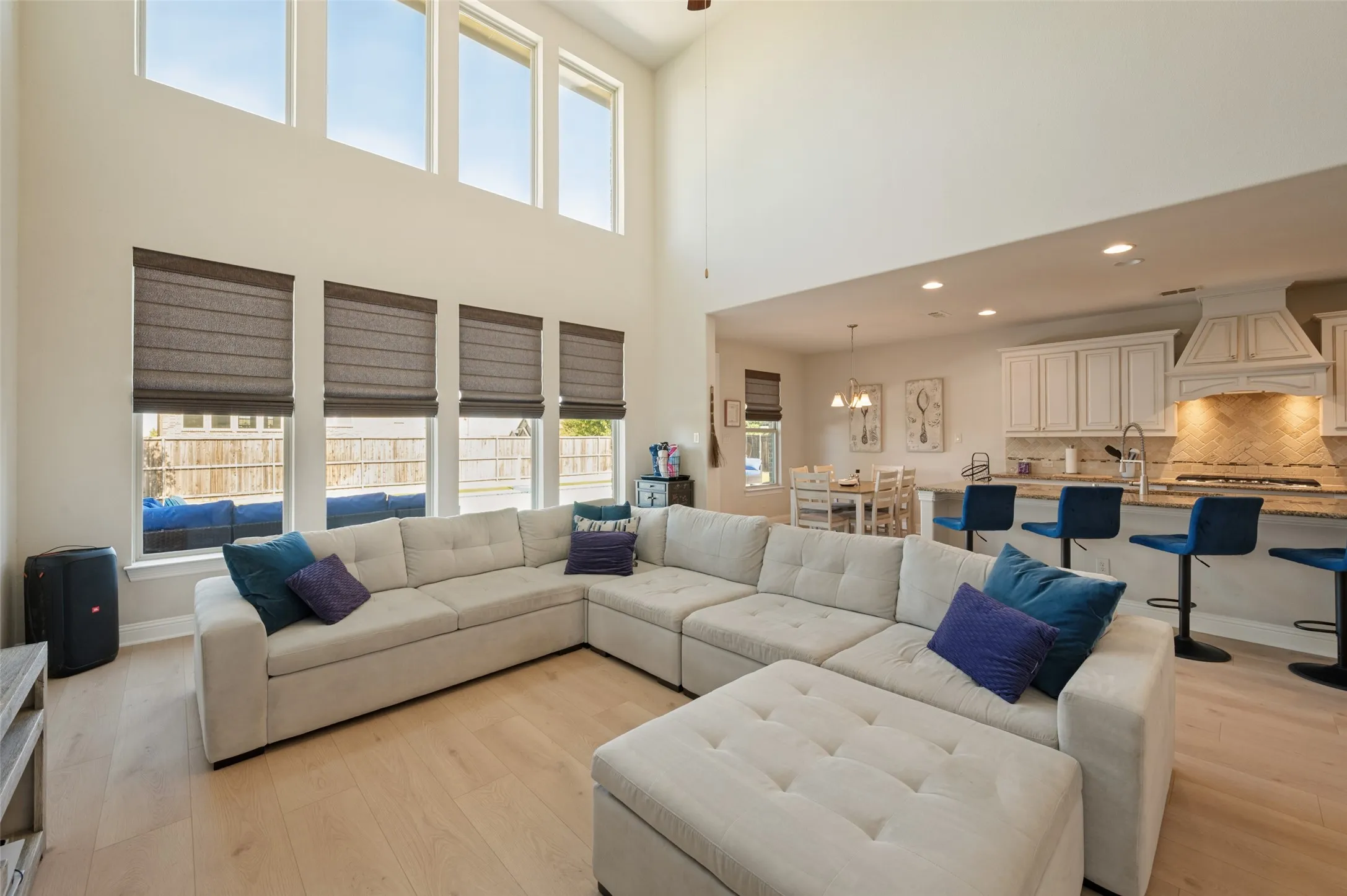 High ceilings with upper transom windows, light wood-finish flooring, recessed lighting, and a kitchen featuring a large island with bar seating