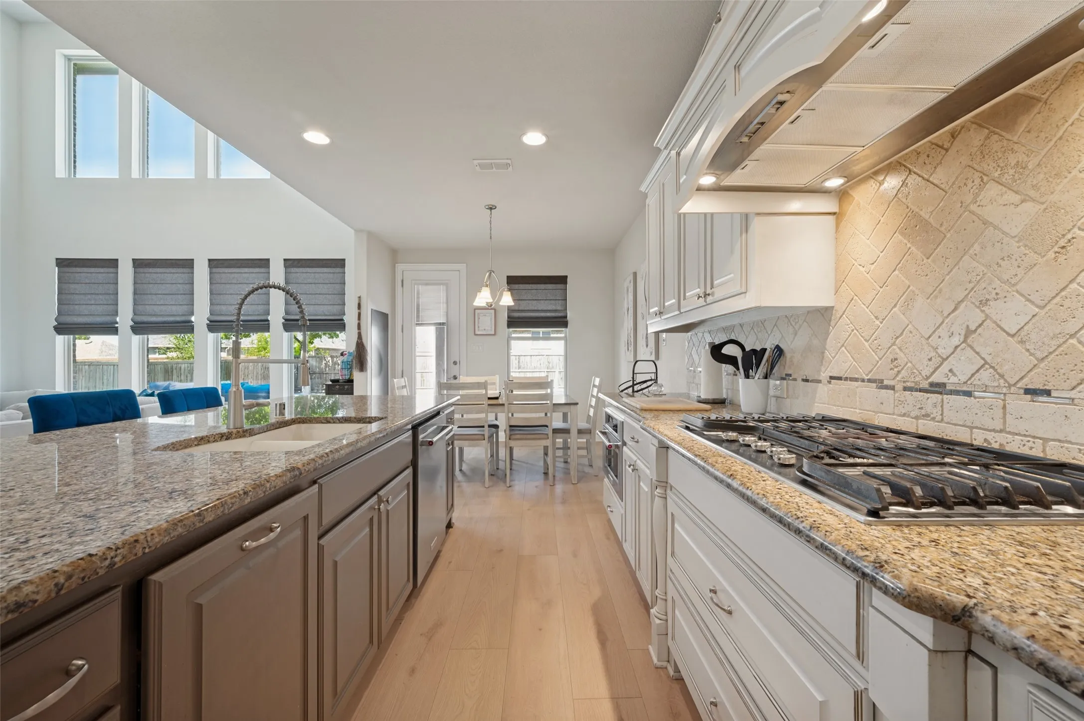 Kitchen featuring granite countertops, wood-finish flooring, stainless steel appliances, a tile backsplash, and recessed lighting
