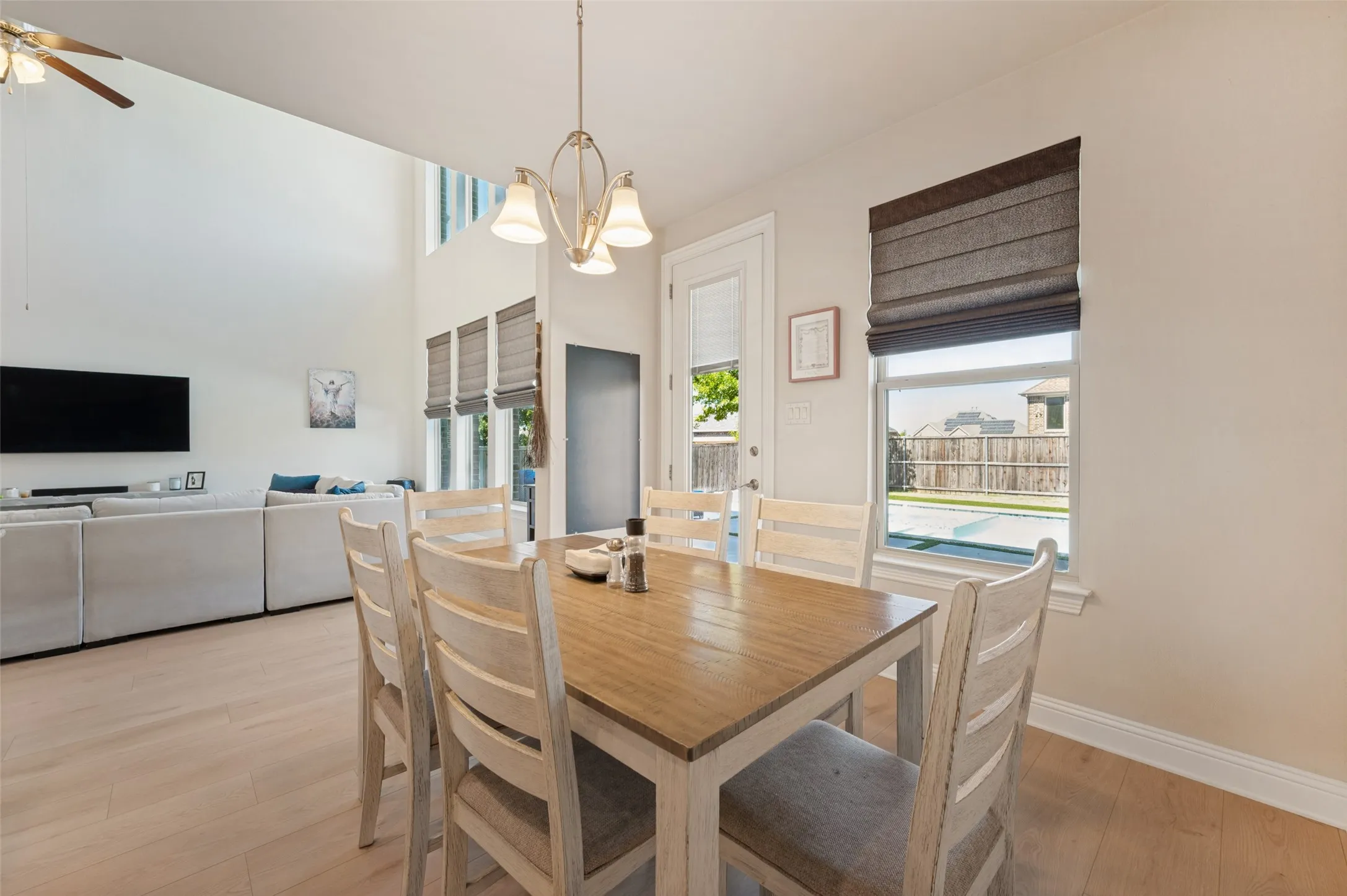Light wood-finish flooring, high vaulted ceiling, and multiple windows with blinds