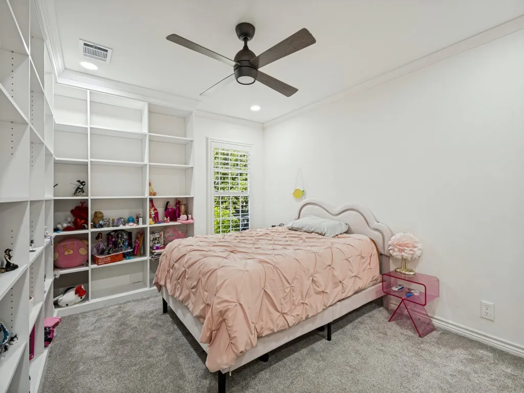 Built-in shelving, recessed lighting, ceiling fan, crown molding, and window with plantation shutters