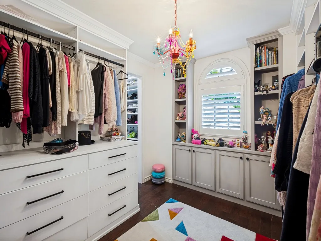 Luxurious walk-in closet featuring dual clothing rods with ample hanging space, multiple built-in drawers with sleek hardware, and custom cabinetry with shelving
