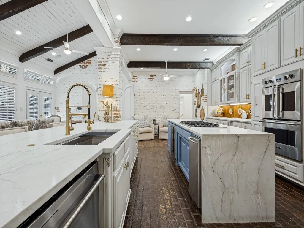 Vaulted ceiling with exposed beams, brick accent walls, and wood-finish flooring