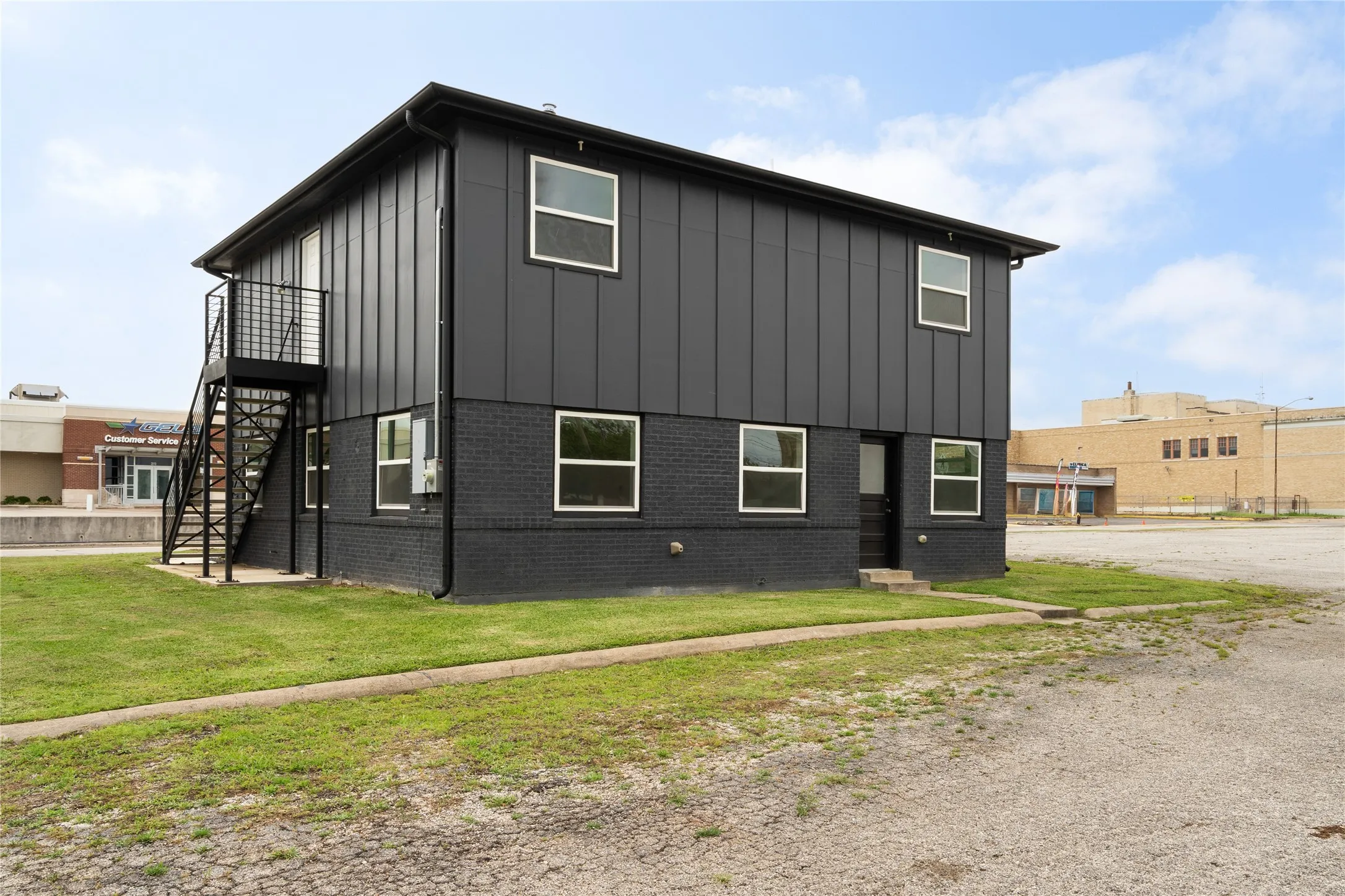 Two-story structure featuring a dark facade with vertical paneling and a brick base