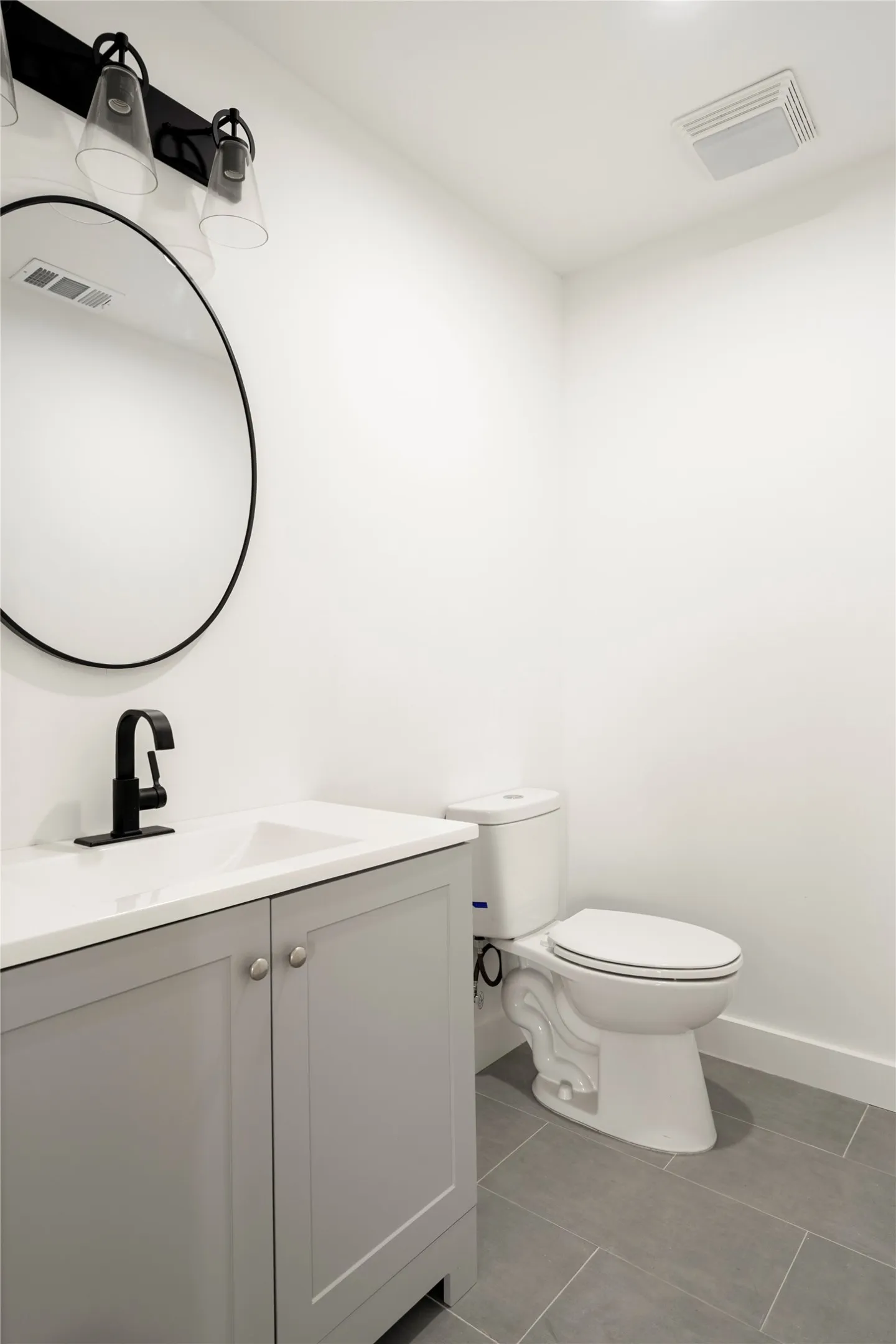 Modern bathroom featuring a single vanity with a light gray cabinet, white countertop, and matte black faucet