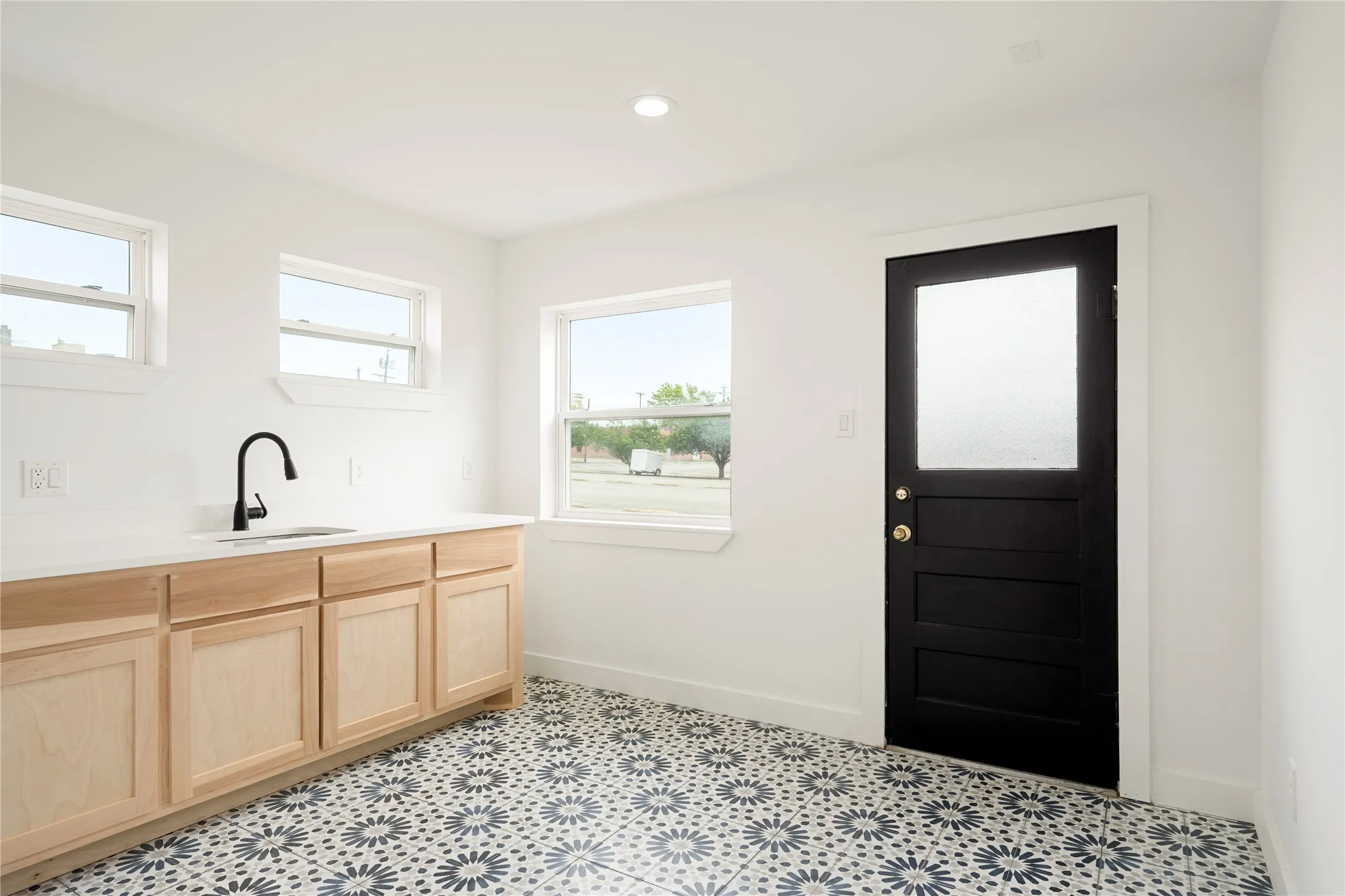 cabinetry with a white countertop and undermount sink with a matte black faucet