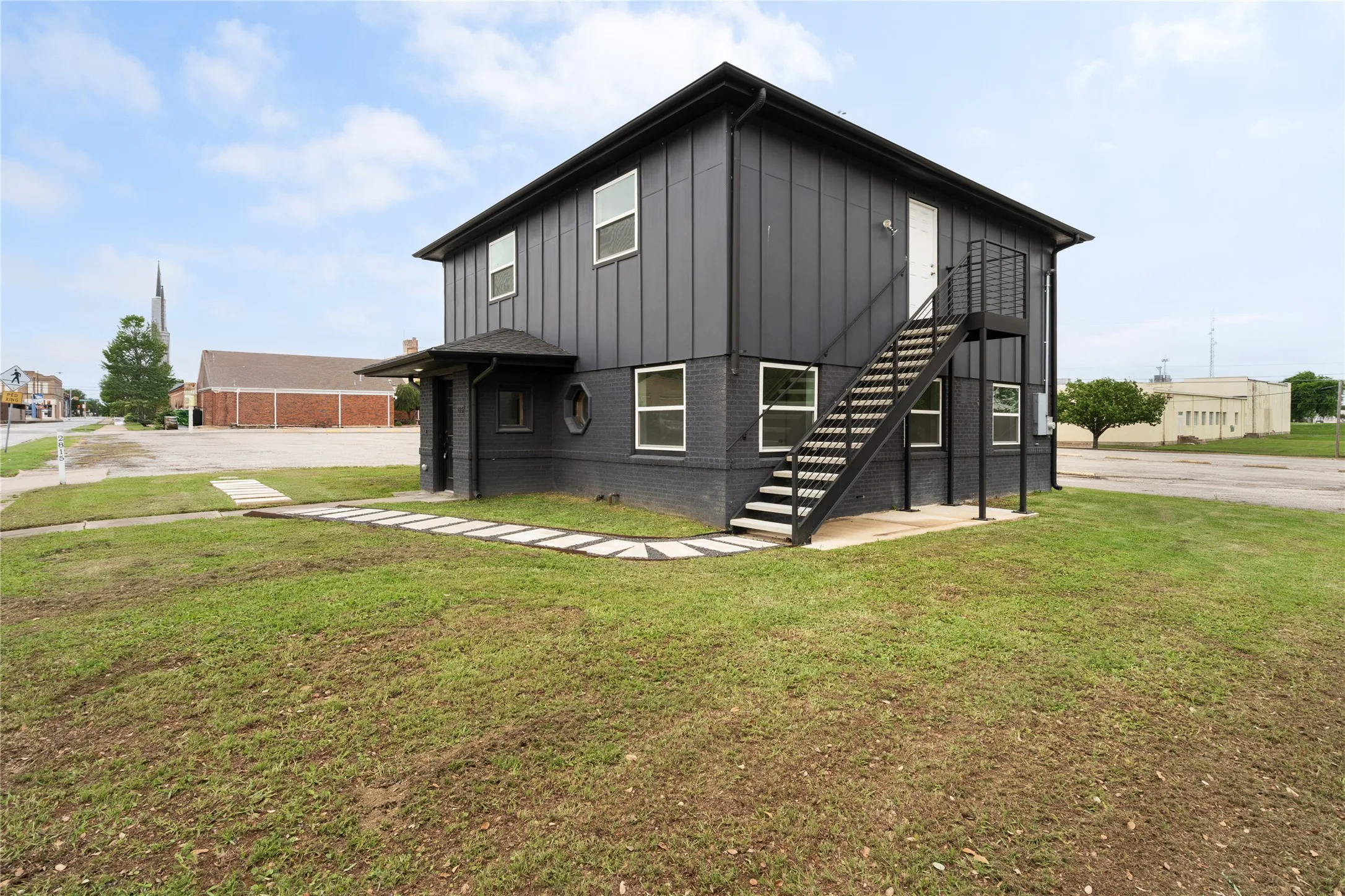 Modern two-story structure with dark vertical siding and painted brick exterior