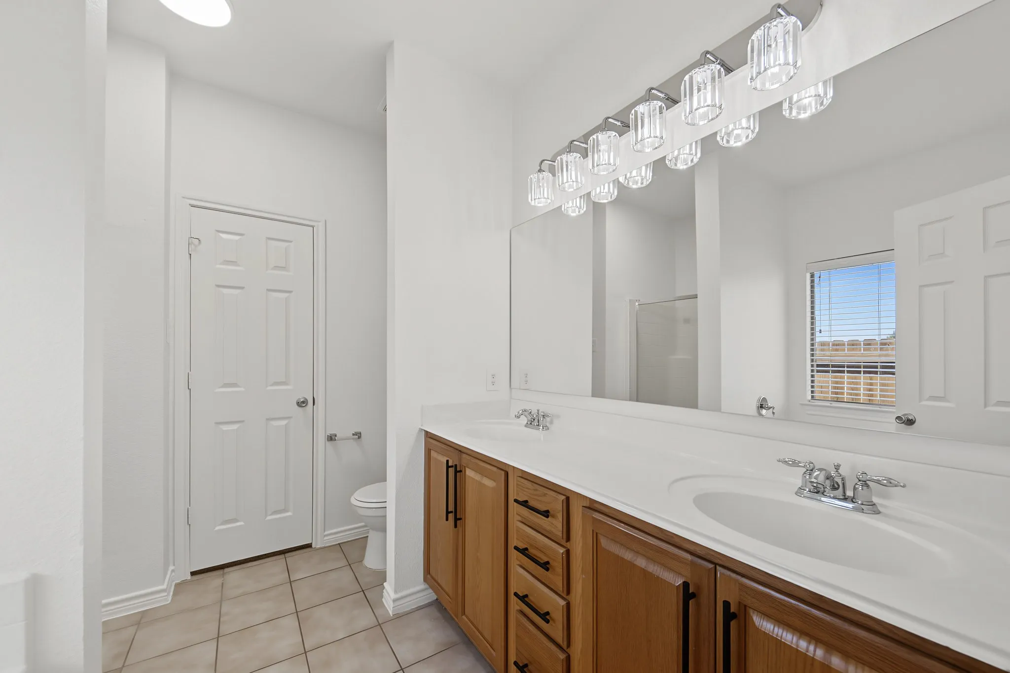 Dual vanity with white countertops, wood cabinetry, and chrome fixtures