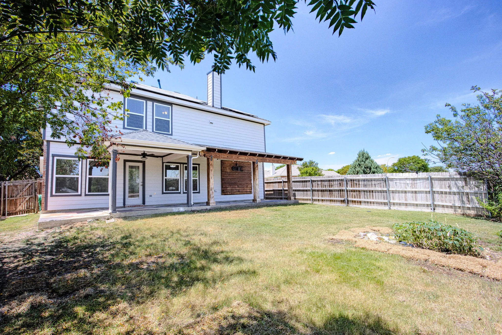 Two-story residence with white siding, covered patio, and attached pergola