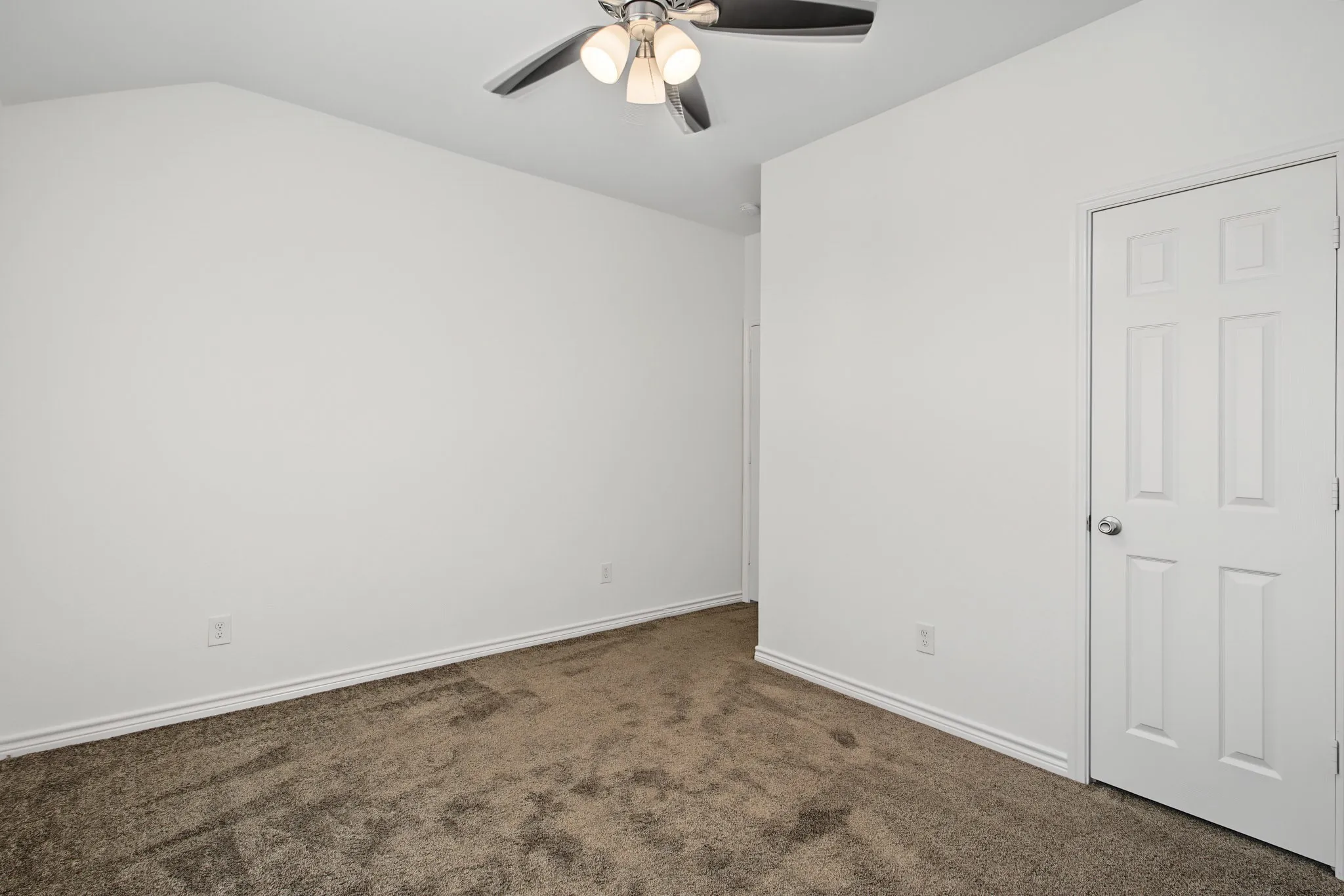 Vaulted ceiling with an attached ceiling fan, neutral wall paint, and carpet flooring