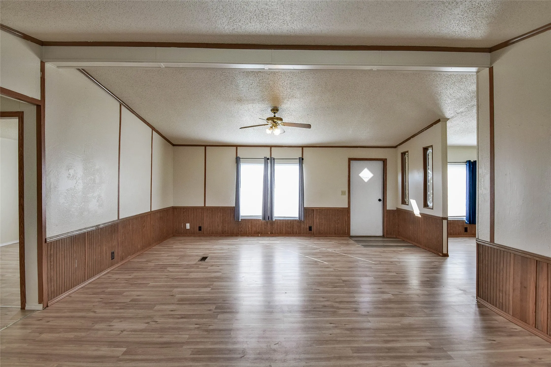 Wood-look vinyl  flooring throughout, ceiling fan with integrated lighting, wood paneling, and multiple windows