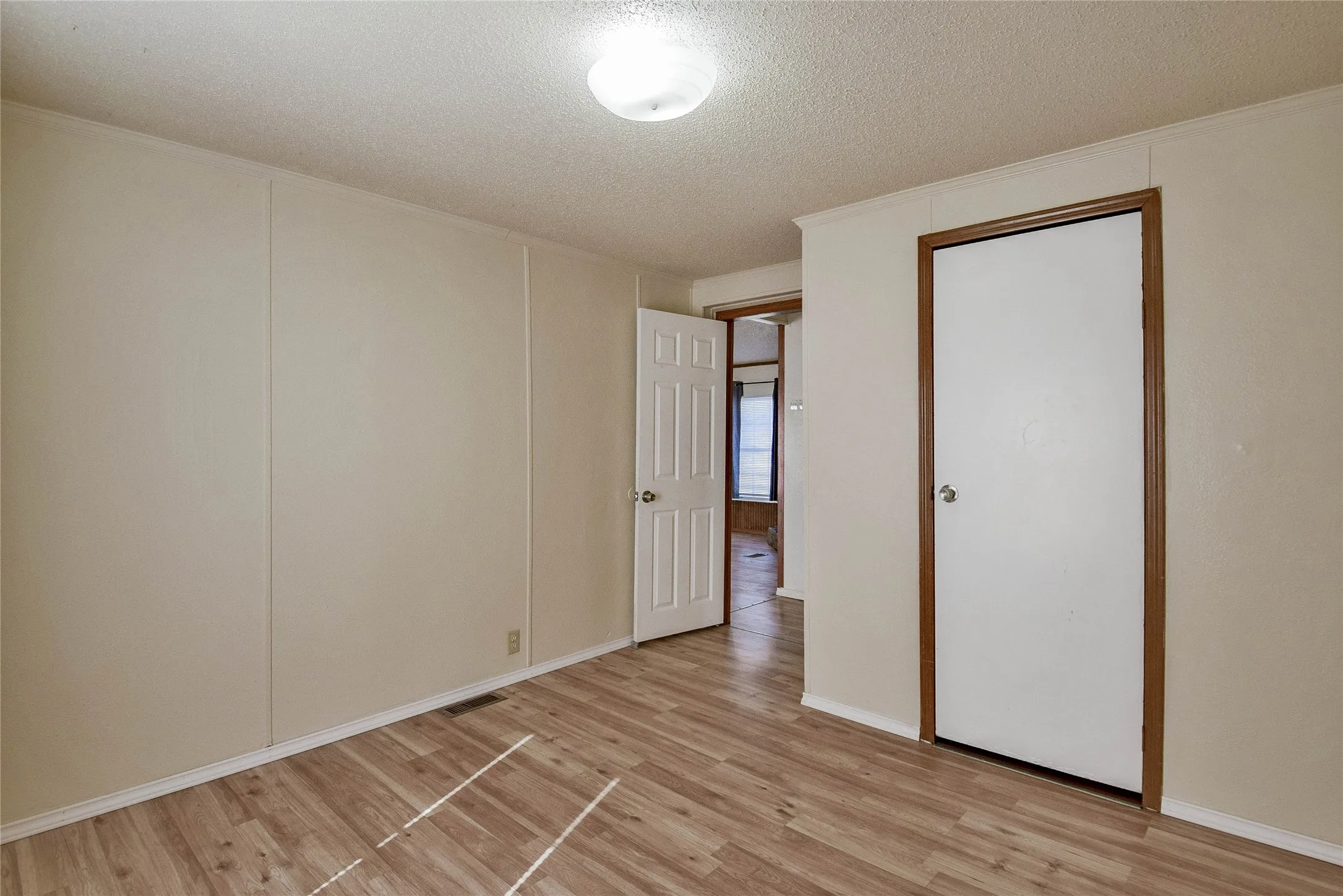 Wood-look vinyl  flooring, paneled walls, and flush mount lighting