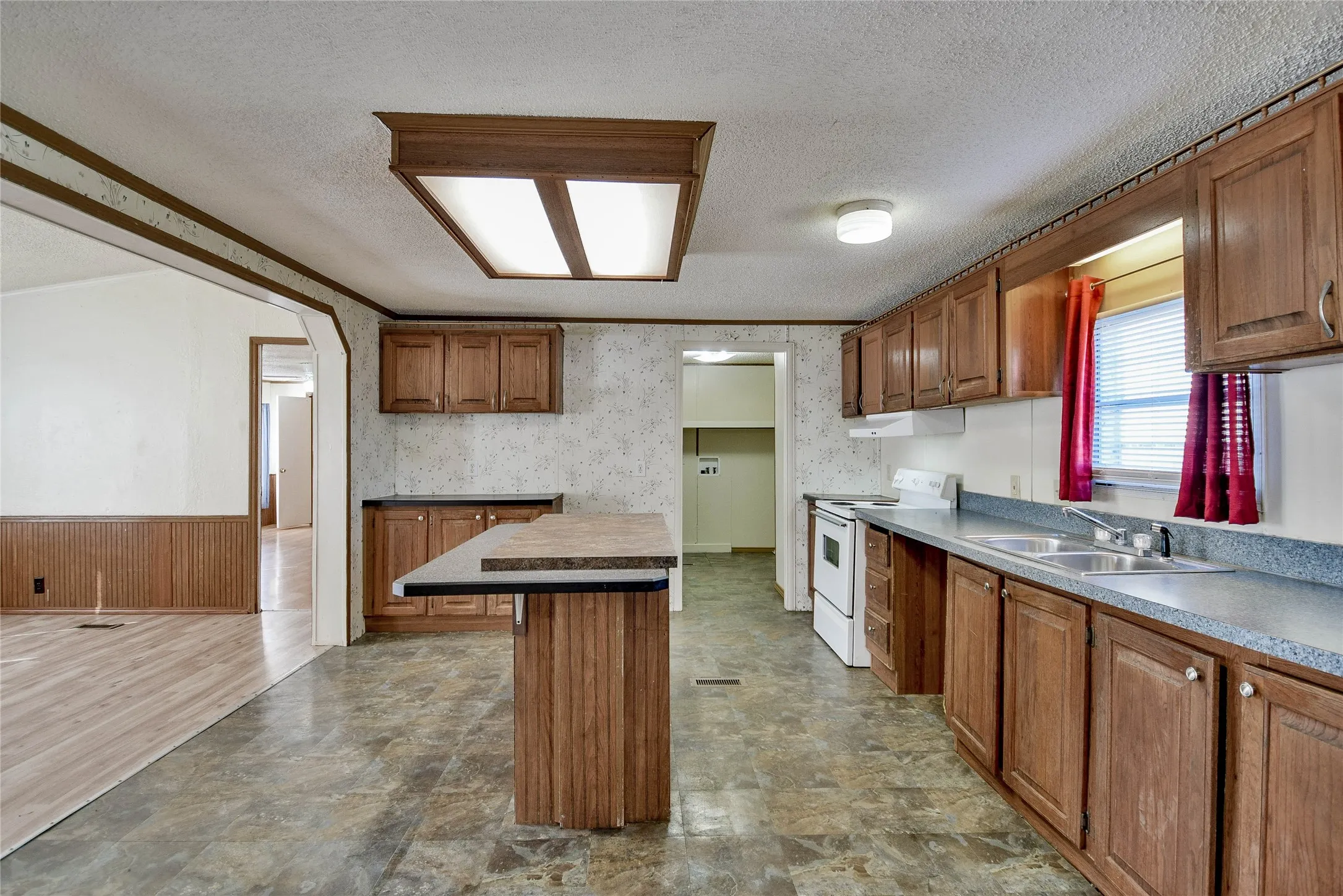Kitchen featuring wood-finish cabinetry, a double basin sink, and an integrated kitchen island