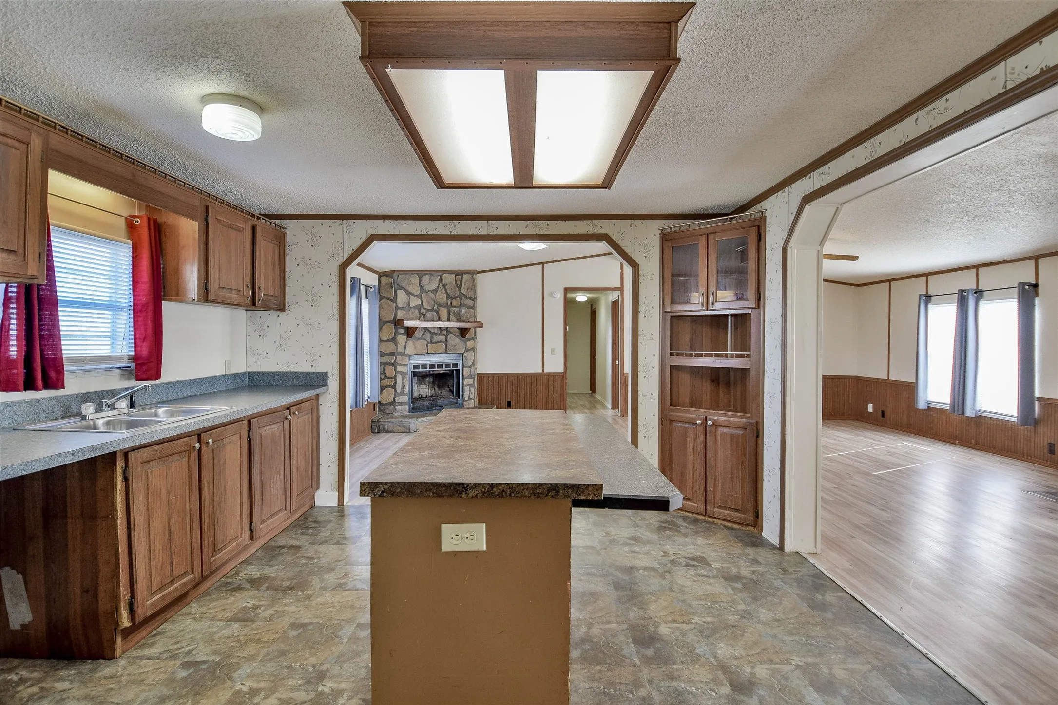 Kitchen featuring wood-finish cabinetry, a double basin sink, and an island counter