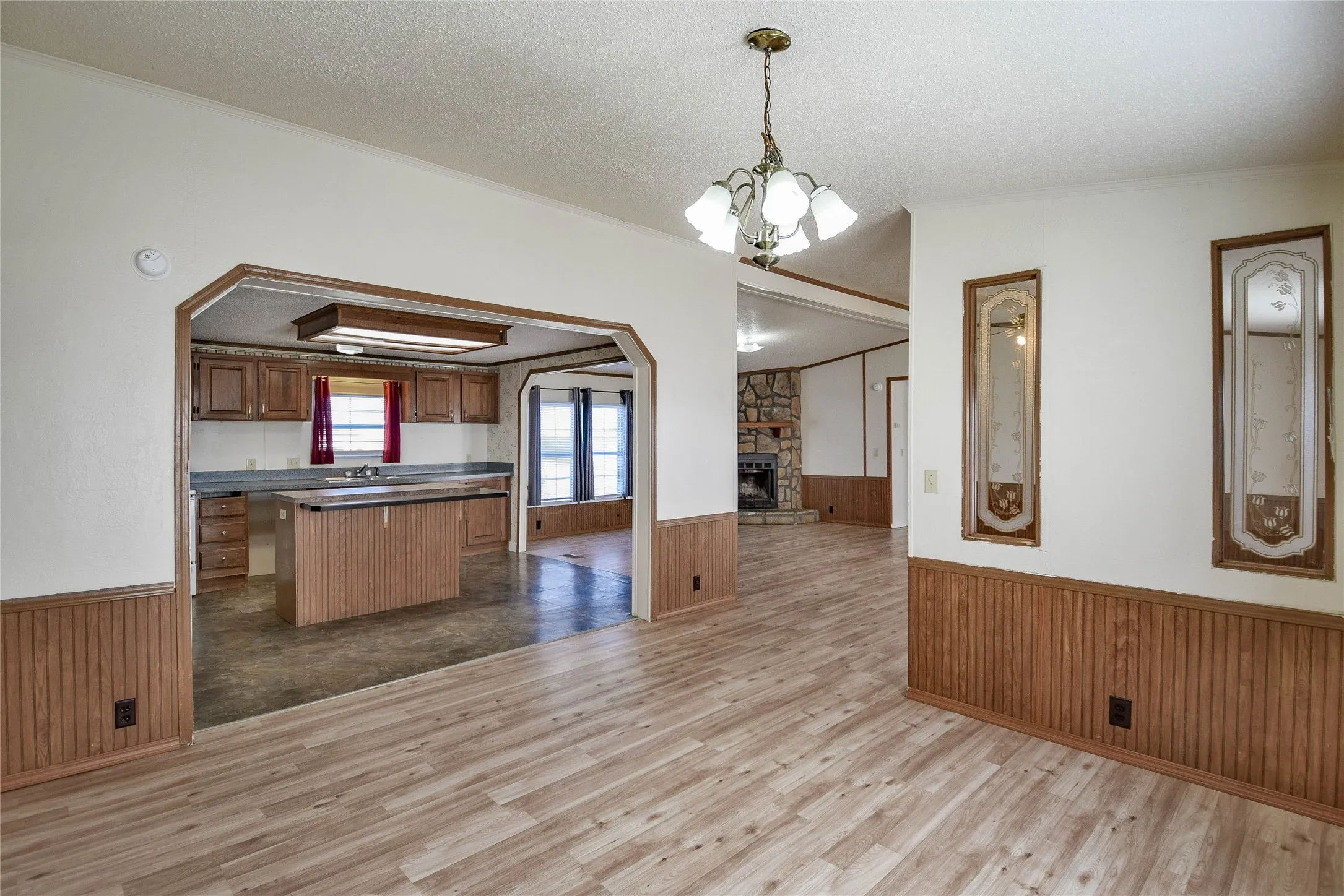 Wood-finish flooring, beadboard wainscoting, and a decorative chandelier