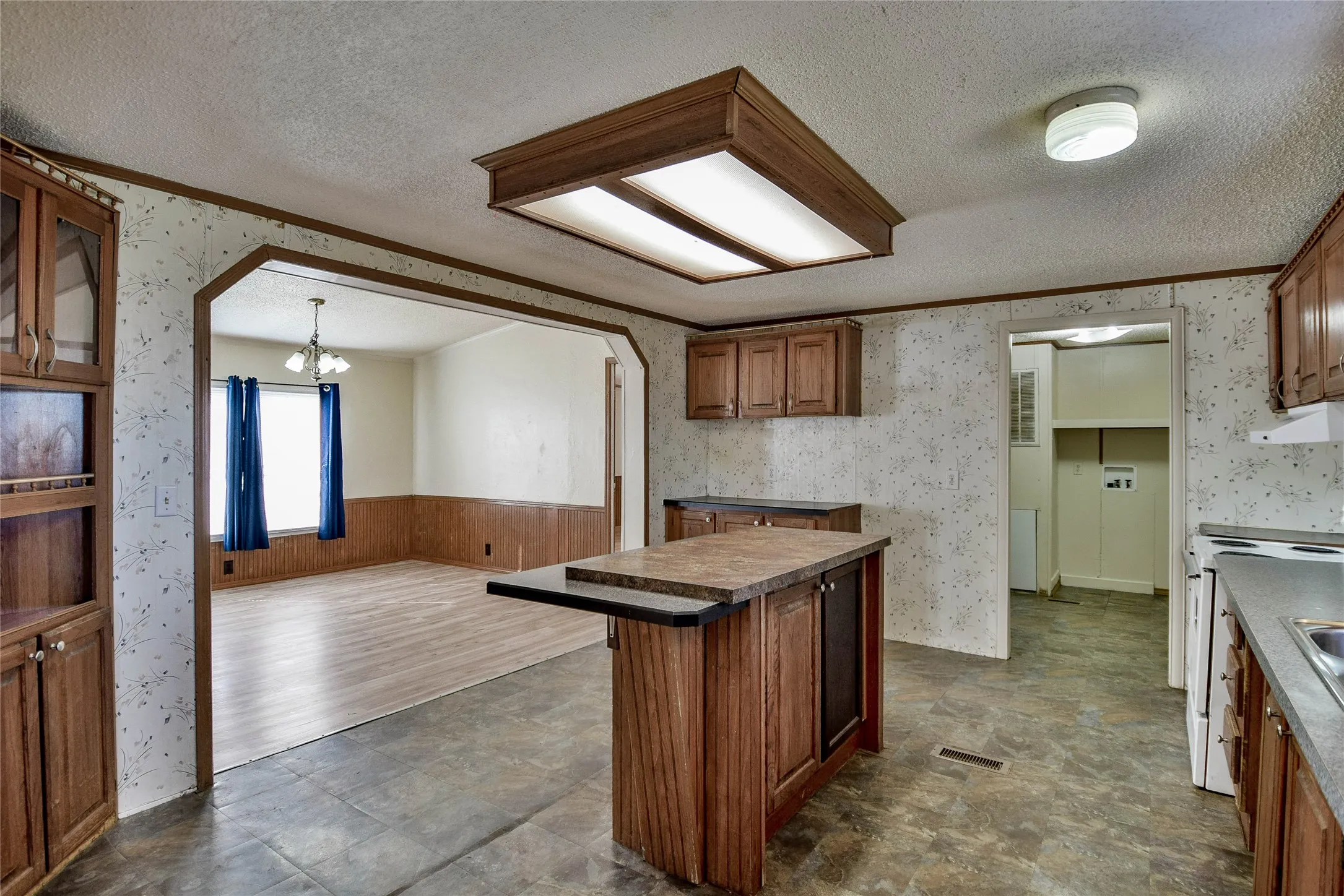 Kitchen featuring wood-finish cabinetry, a central island with an extended countertop, and a built-in electric range
