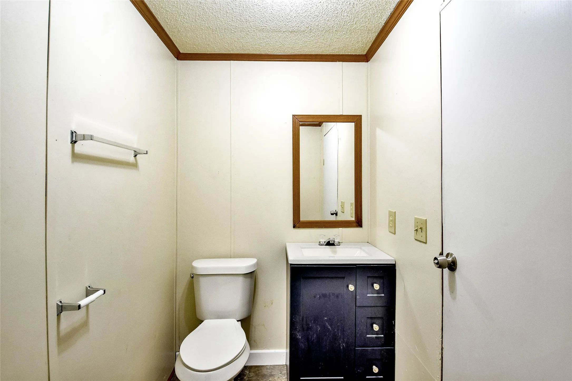 Half bathroom featuring a vanity with an integrated sink, framed mirror, and a white toilet