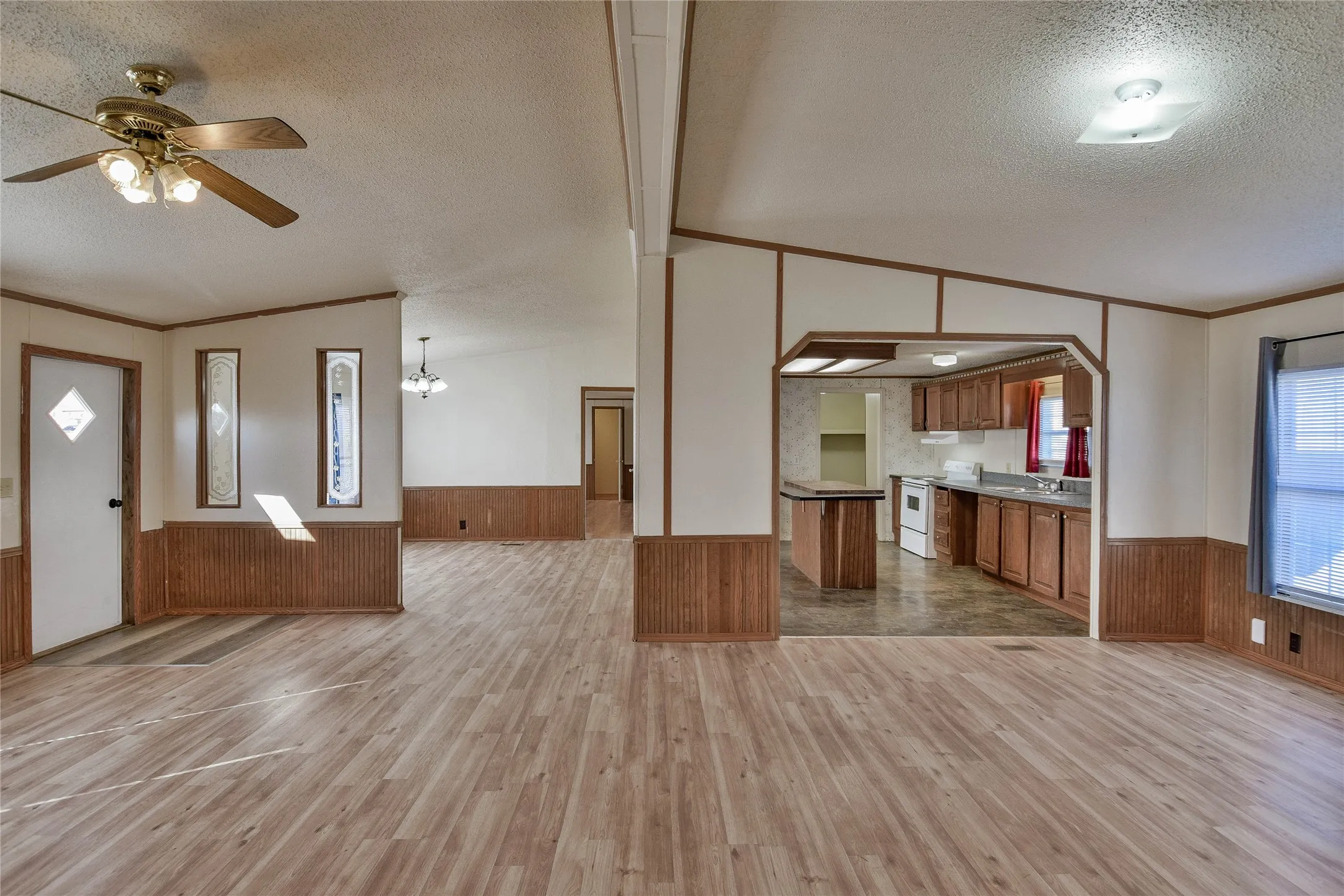 Wood-look vinyl - flooring throughout, with a ceiling fan in the foreground and recessed lighting in the kitchen