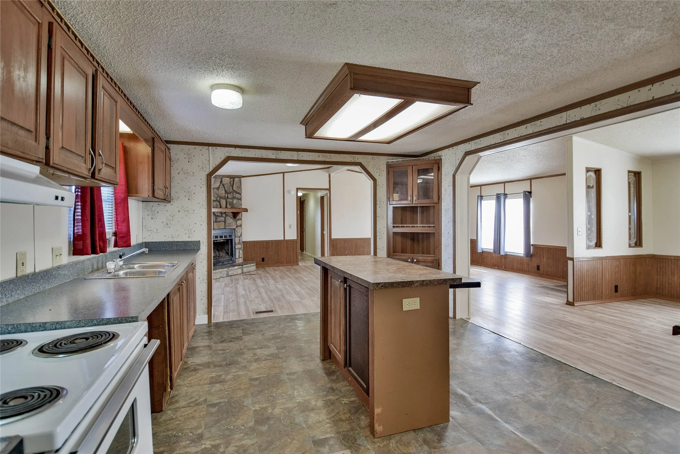 Kitchen featuring wood-finish cabinetry, a built-in oven, and a double basin sink