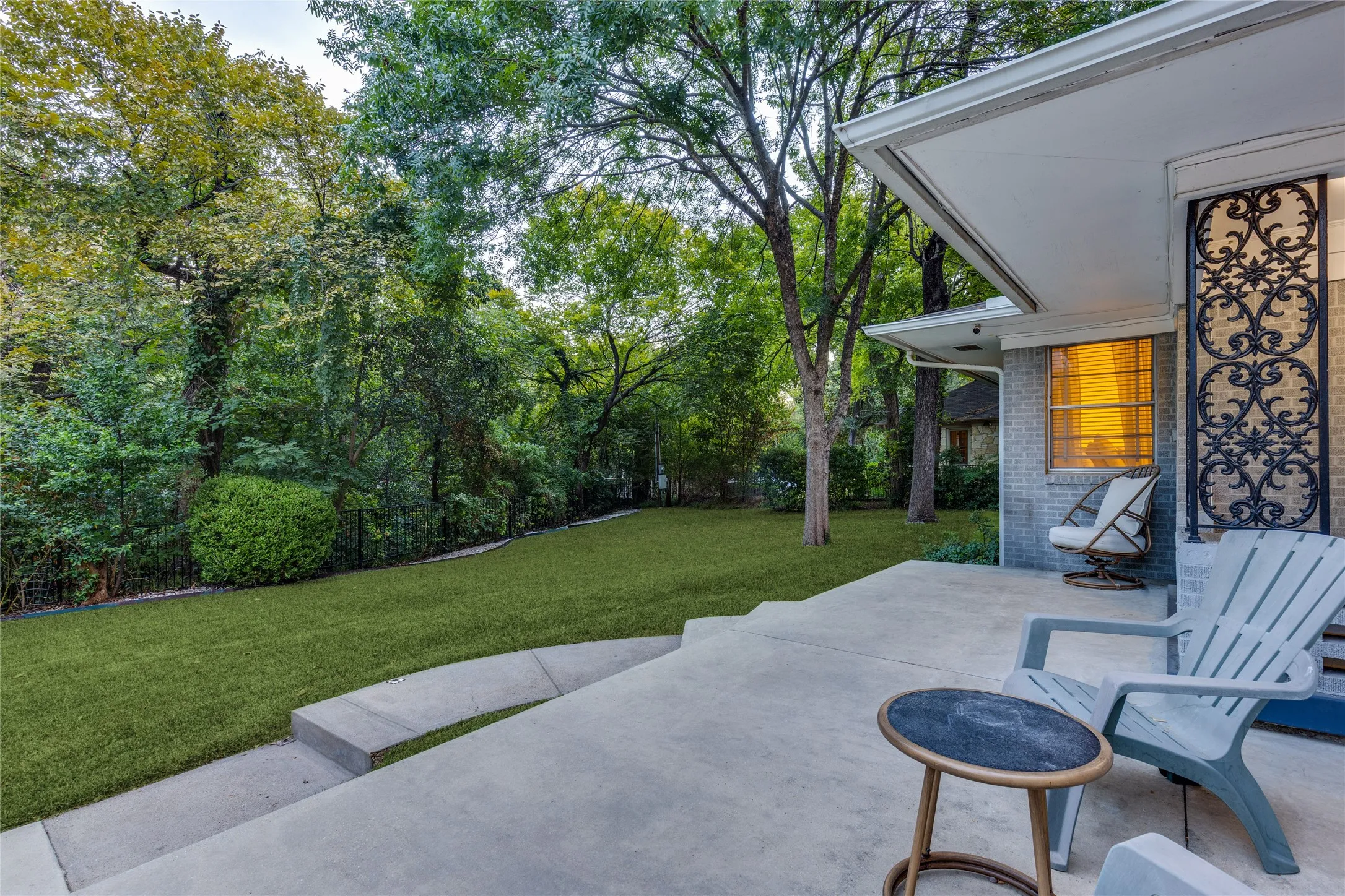 Outdoor living beneath mature trees, with the creek and surrounding greenery close at hand.