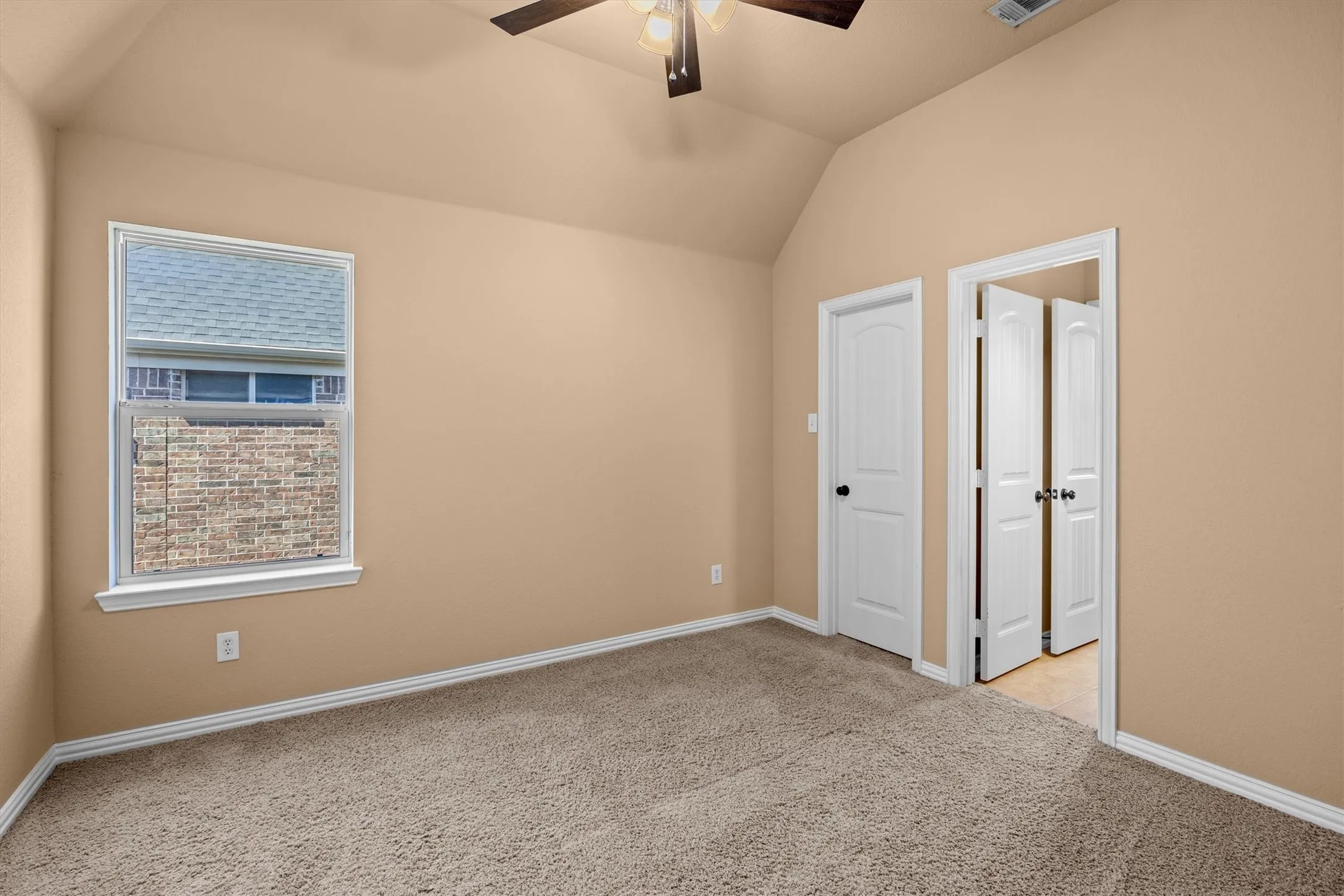 This comfortable additional bedroom features a ceiling fan, natural light, and convenient bathroom access.
