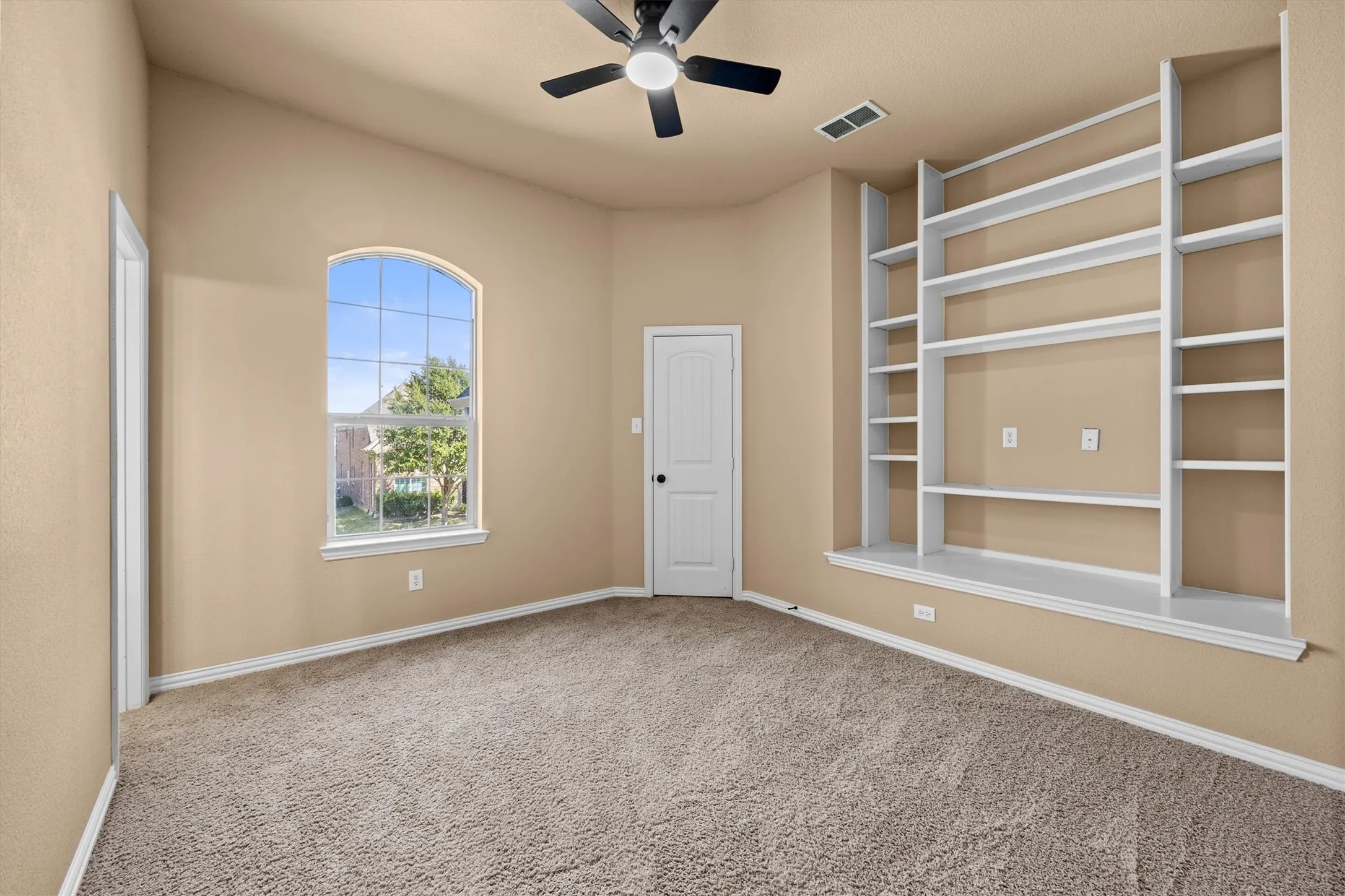 A large arched window and wall of built-in shelves make this room feel bright and inviting!